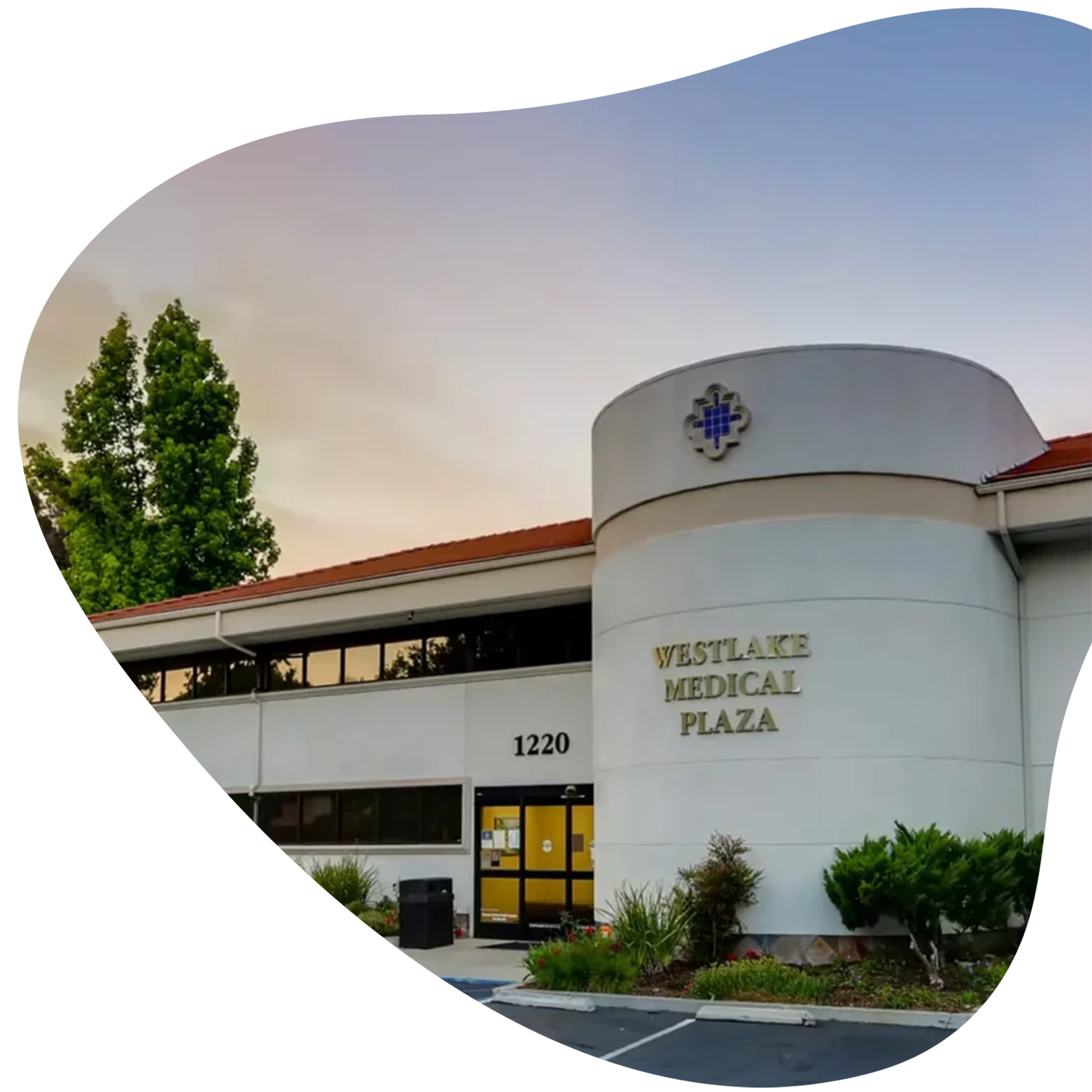 Exterior of Westlake Medical Plaza with white facade, modern design, and landscaping at the entrance. The building's sign is partially visible.