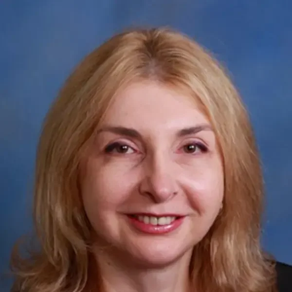 A smiling woman with blonde hair against a blue background.