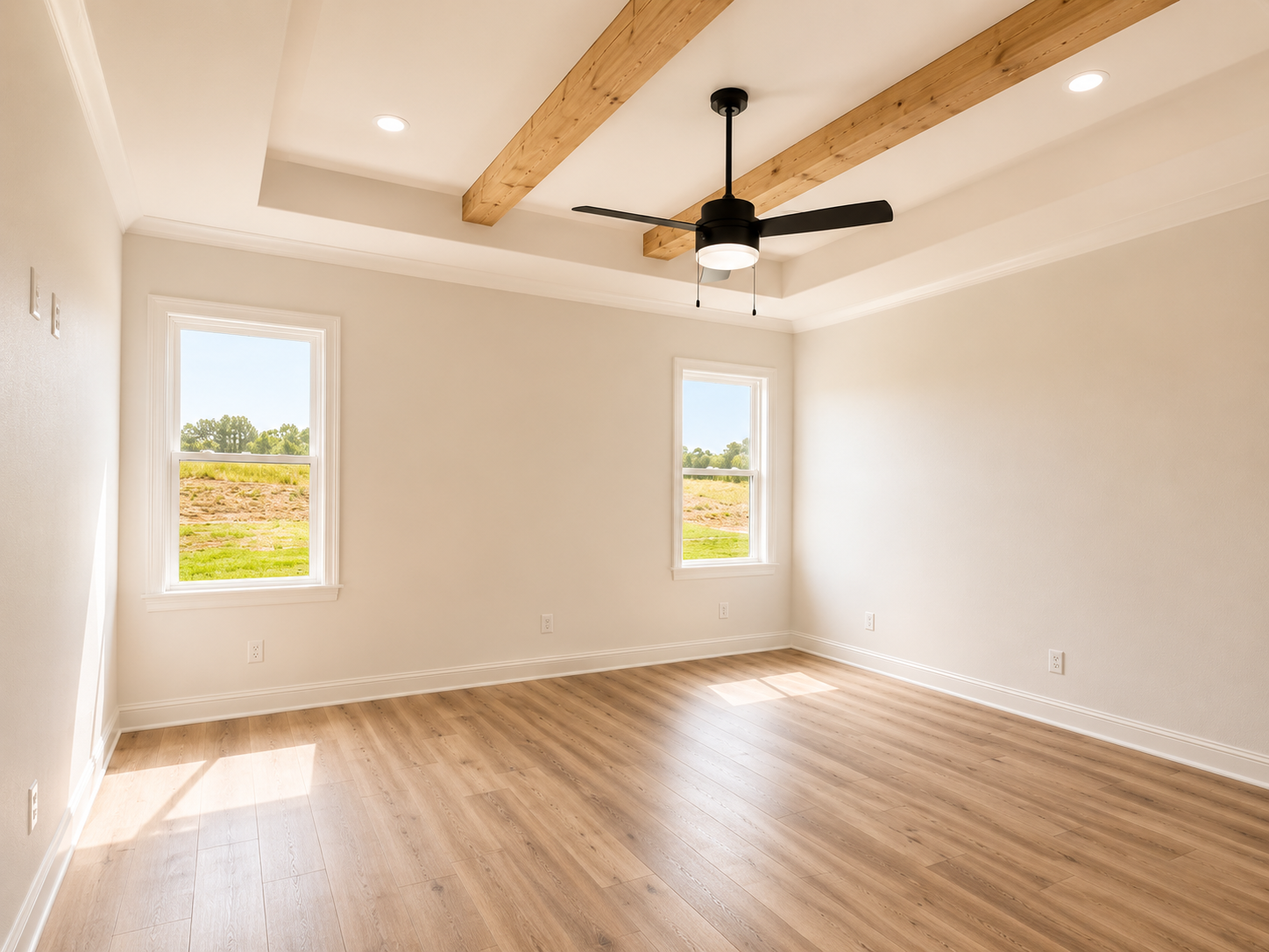 Empty room with wooden floors, two windows, white walls, a ceiling fan with a light, and wooden beams on the ceiling.