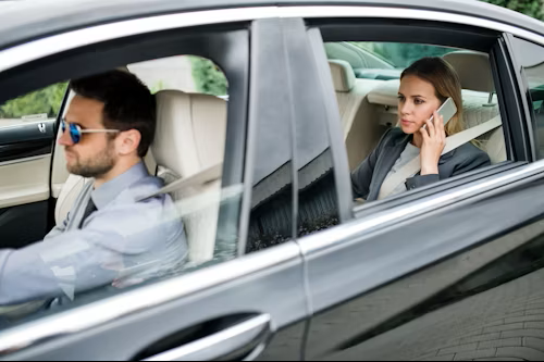 A man driving a car with a woman sitting in the passenger seat on the phone.