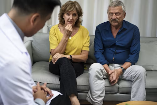 A healthcare professional consulting with an older couple in a medical office.