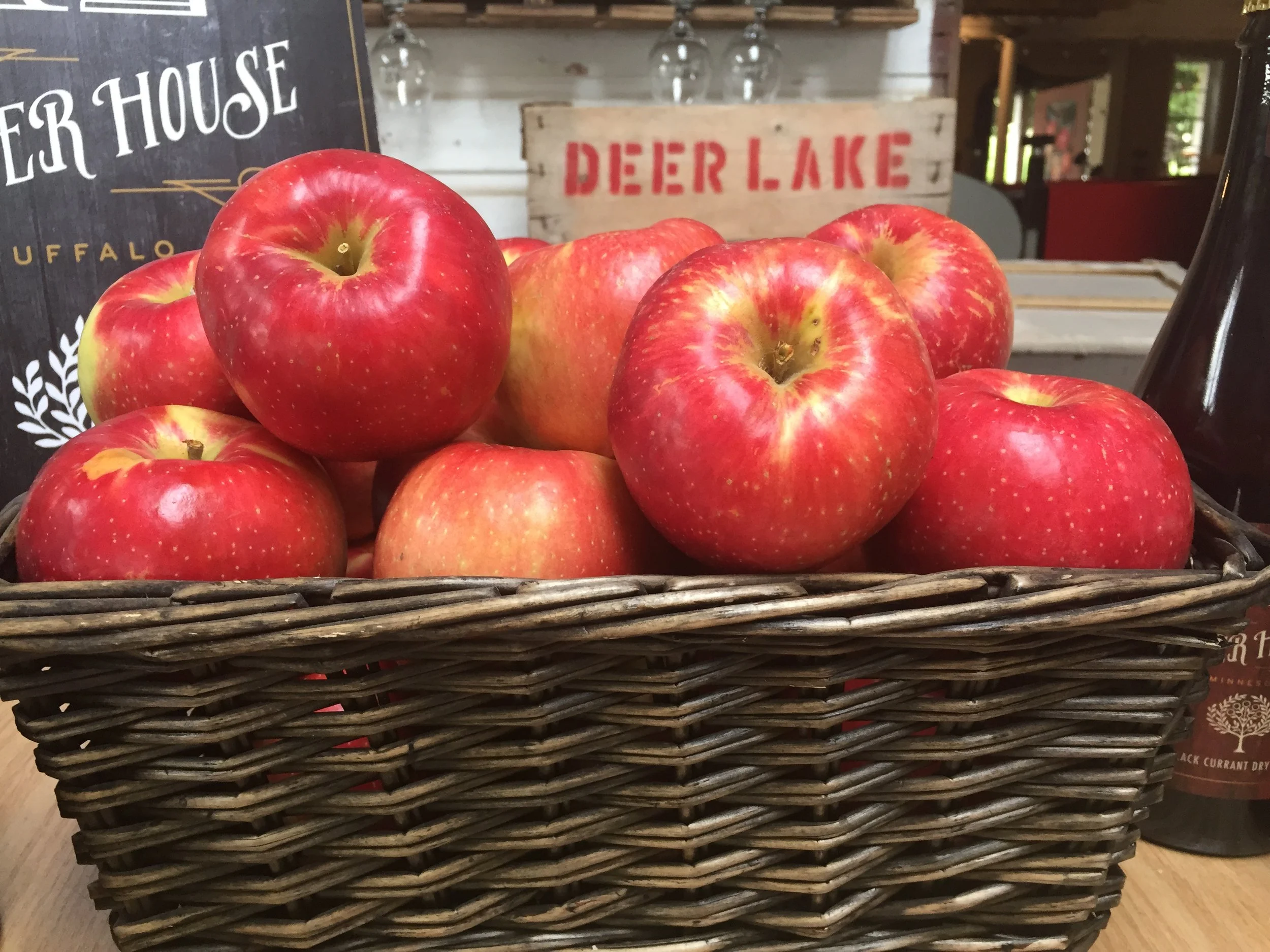 A wicker basket filled with red and yellow apples on display in a rustic store setting.