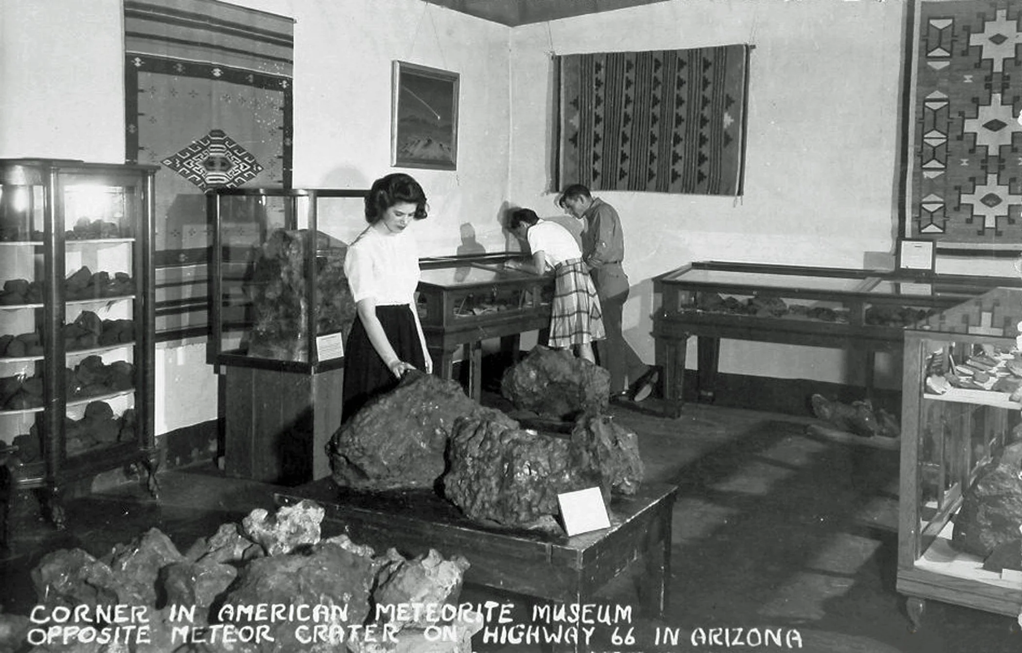 Black and white photo showing a small group of people observing meteorites inside the American Meteorite Museum in 1946, north of Meteor Crater, outside of Winslow, Arizona.