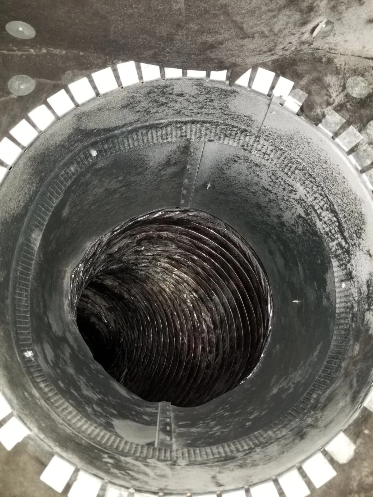 Inside view of a deep industrial metal pipe with a spiral structure.