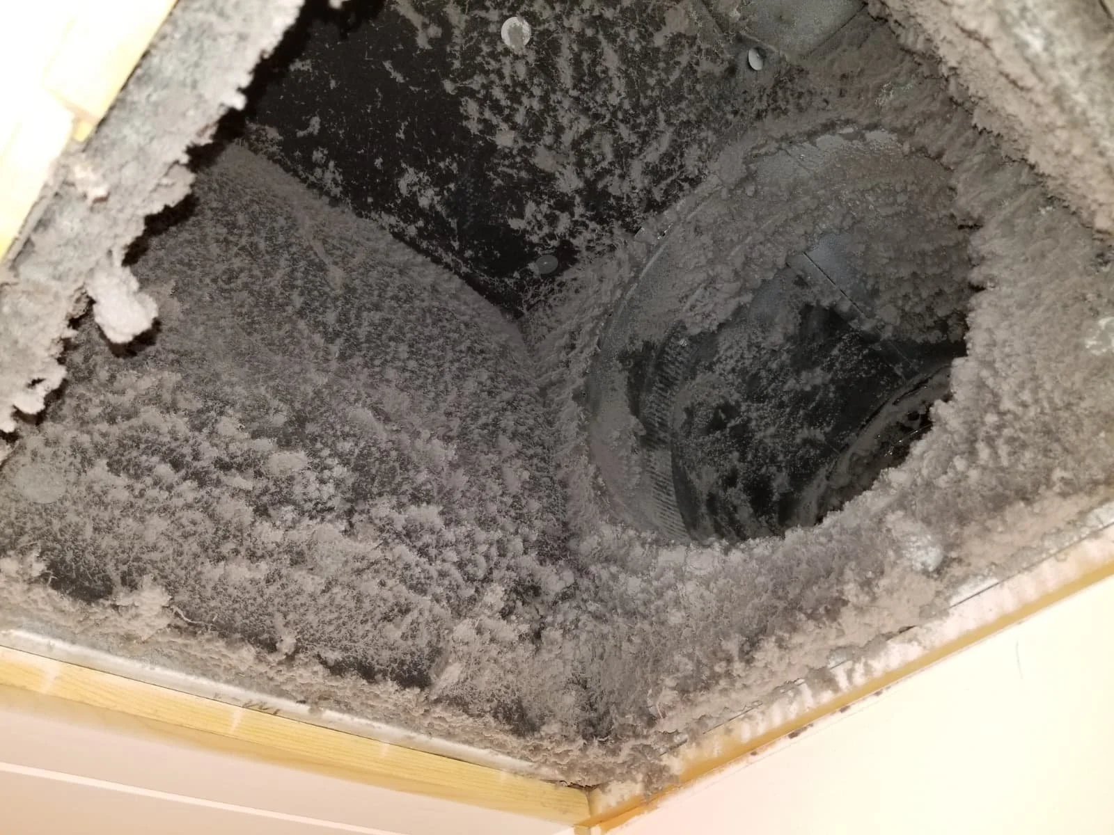 The inside of a ventilation duct shows dust and debris accumulated on the surfaces.