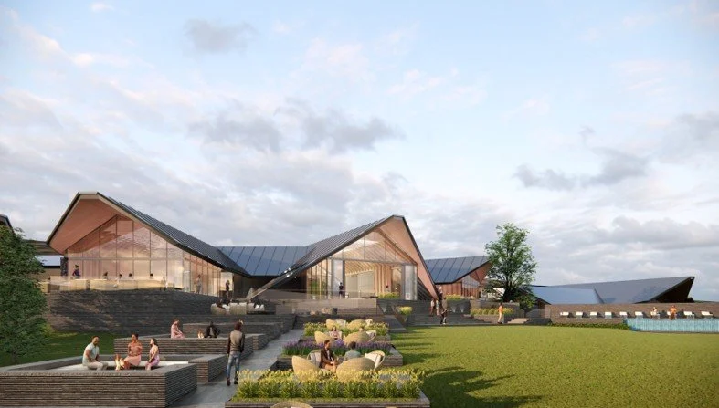 Modern architectural building with glass walls and multiple angular rooflines, surrounded by outdoor seating and landscaped greenery, under a cloudy sky. This is a rendering for a luxury resort that Ten Talents Management is working on.