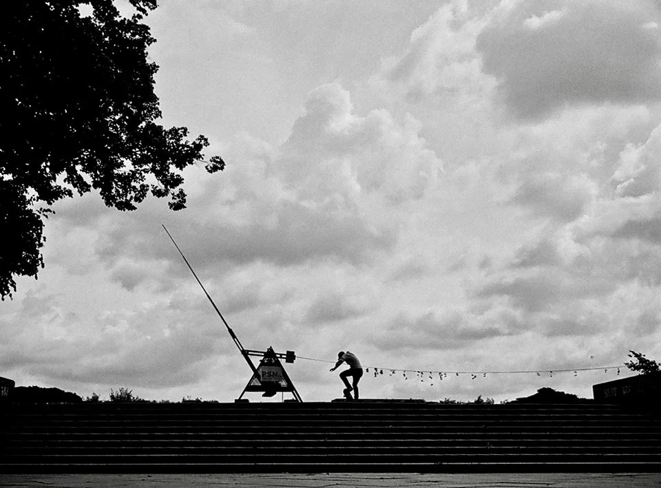 A person adjusting a large antenna on a rooftop with a cloudy sky in the background.