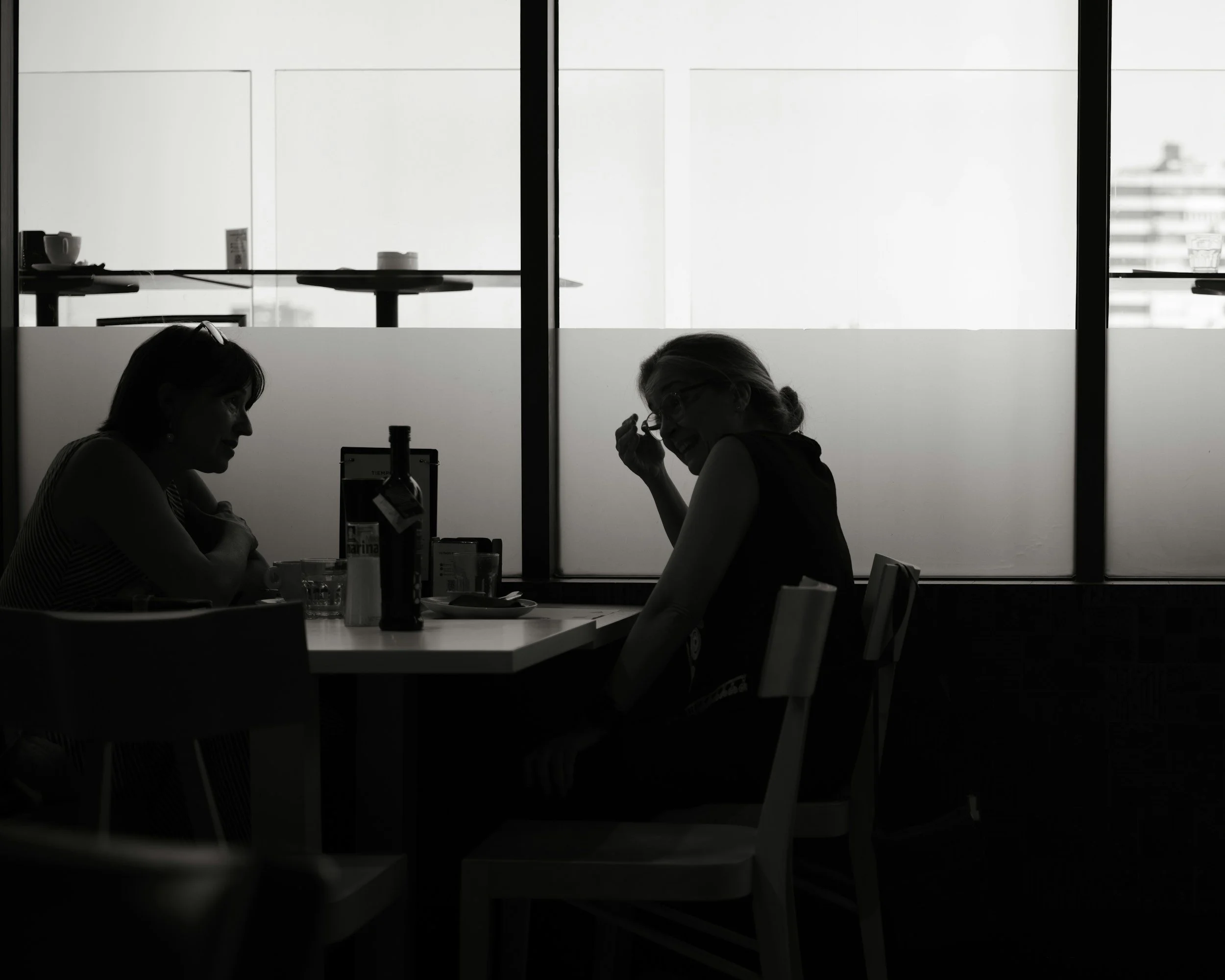 Two women having a serious conversation across a table, representing how to talk with someone struggling with addiction