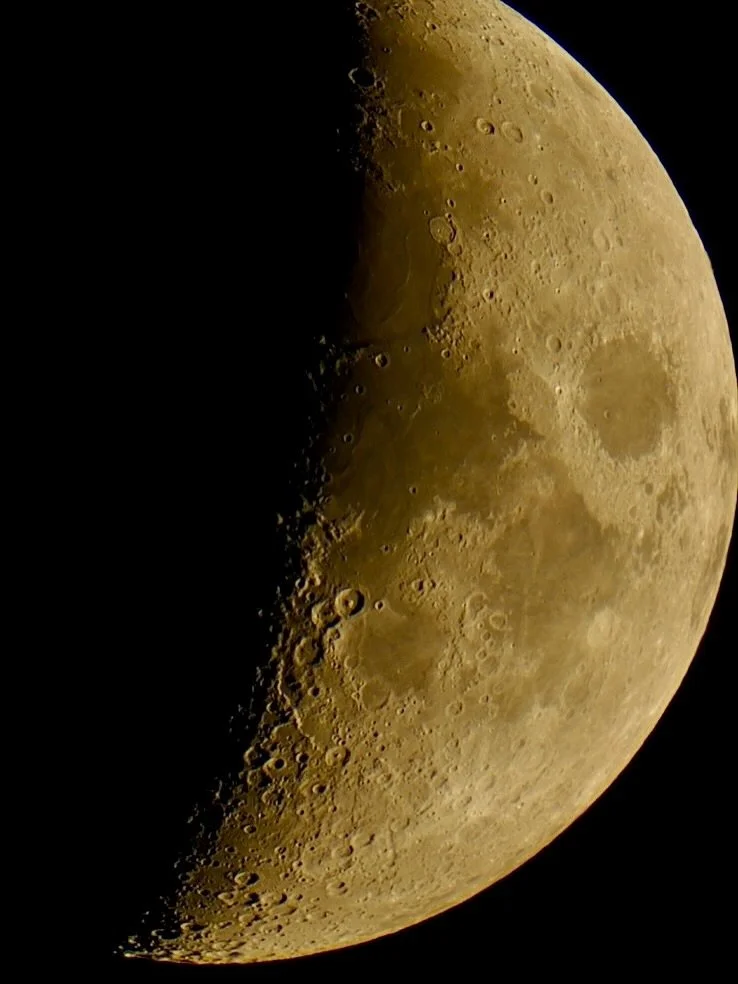 Close-up image of the moon showing craters and surface details, with a shadow cast on part of it.