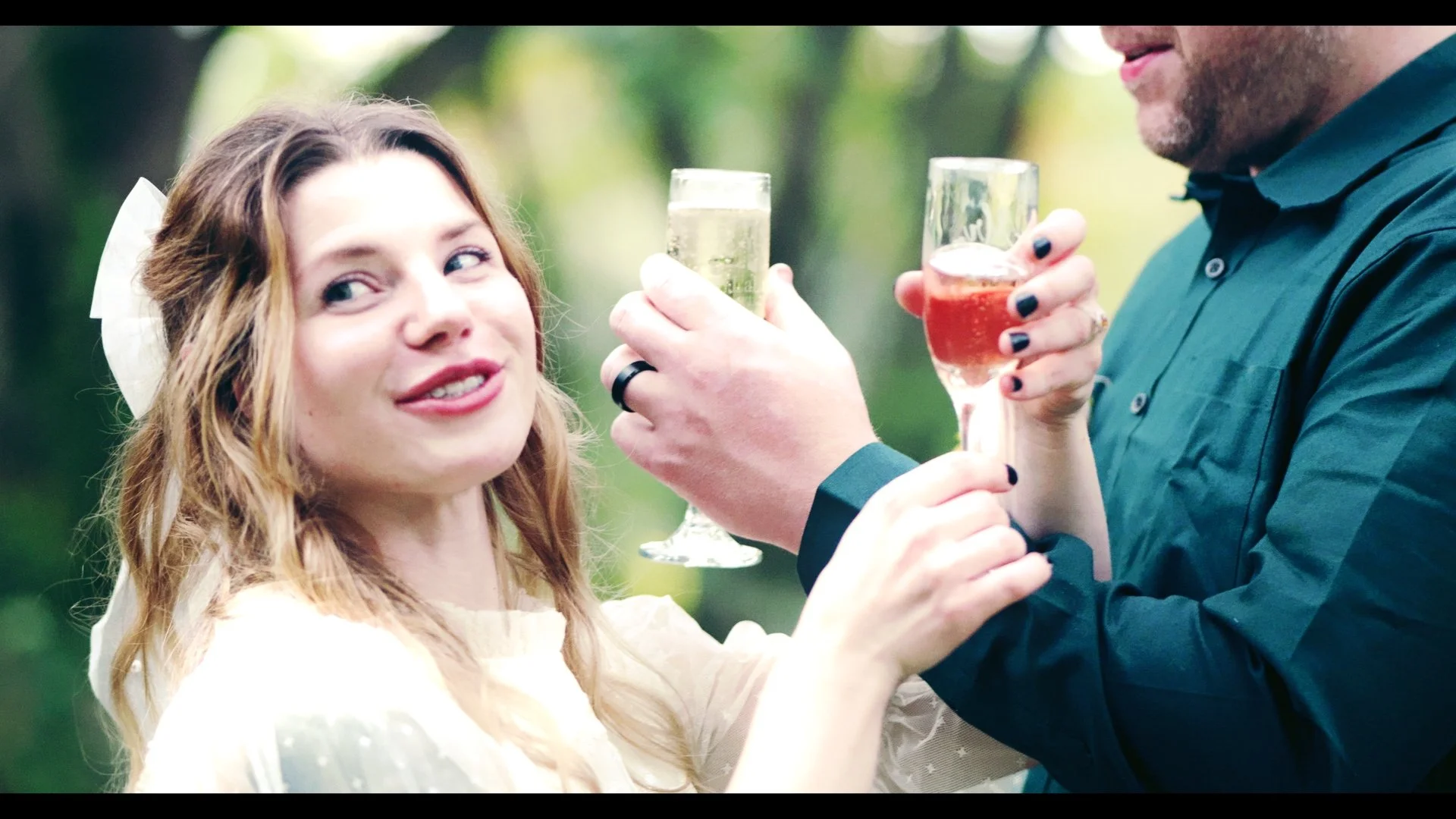 A man and woman clinking glasses of champagne outdoors, smiling and enjoying a celebratory moment.