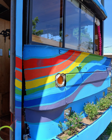 Colorful painted food truck with rainbow stripes and flower boxes underneath.