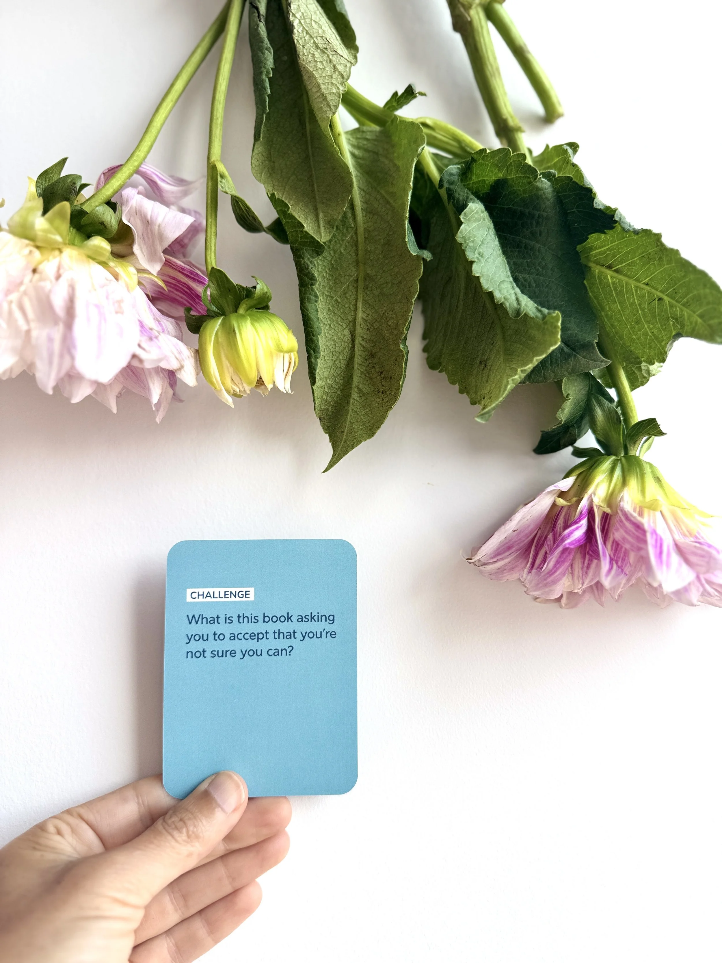 Hand holding a blue Challenge question card with flowers