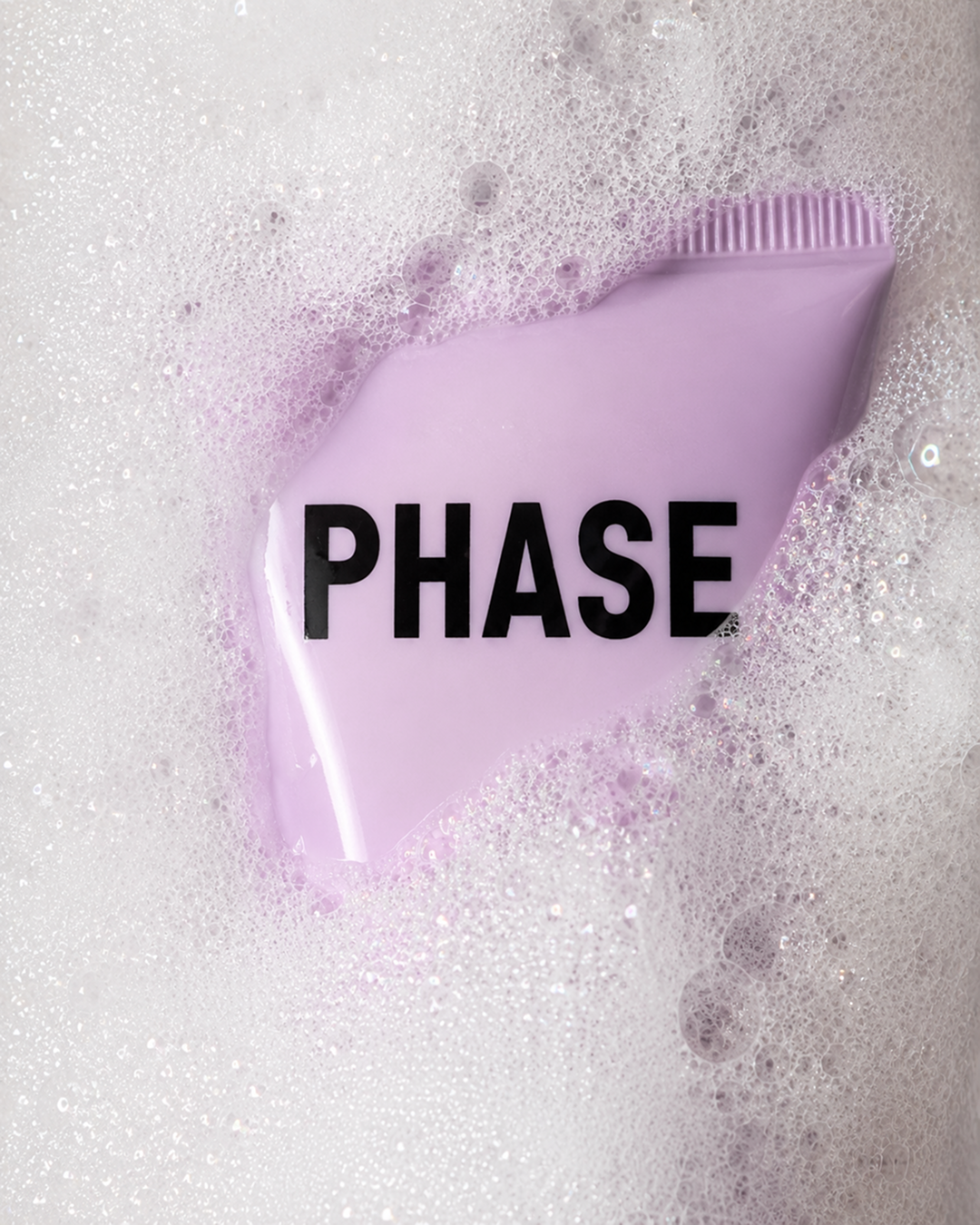 Purple soap with the PHASE skincare logo on it, surrounded by soap bubbles.