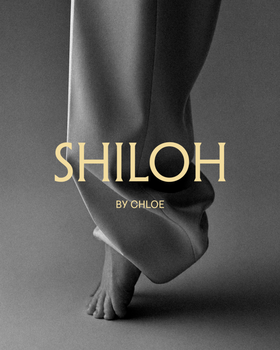 Black and white image of a person's feet and legs pulling on pants, with the Shiloh by Chloe brand in yellow overlayed on top.