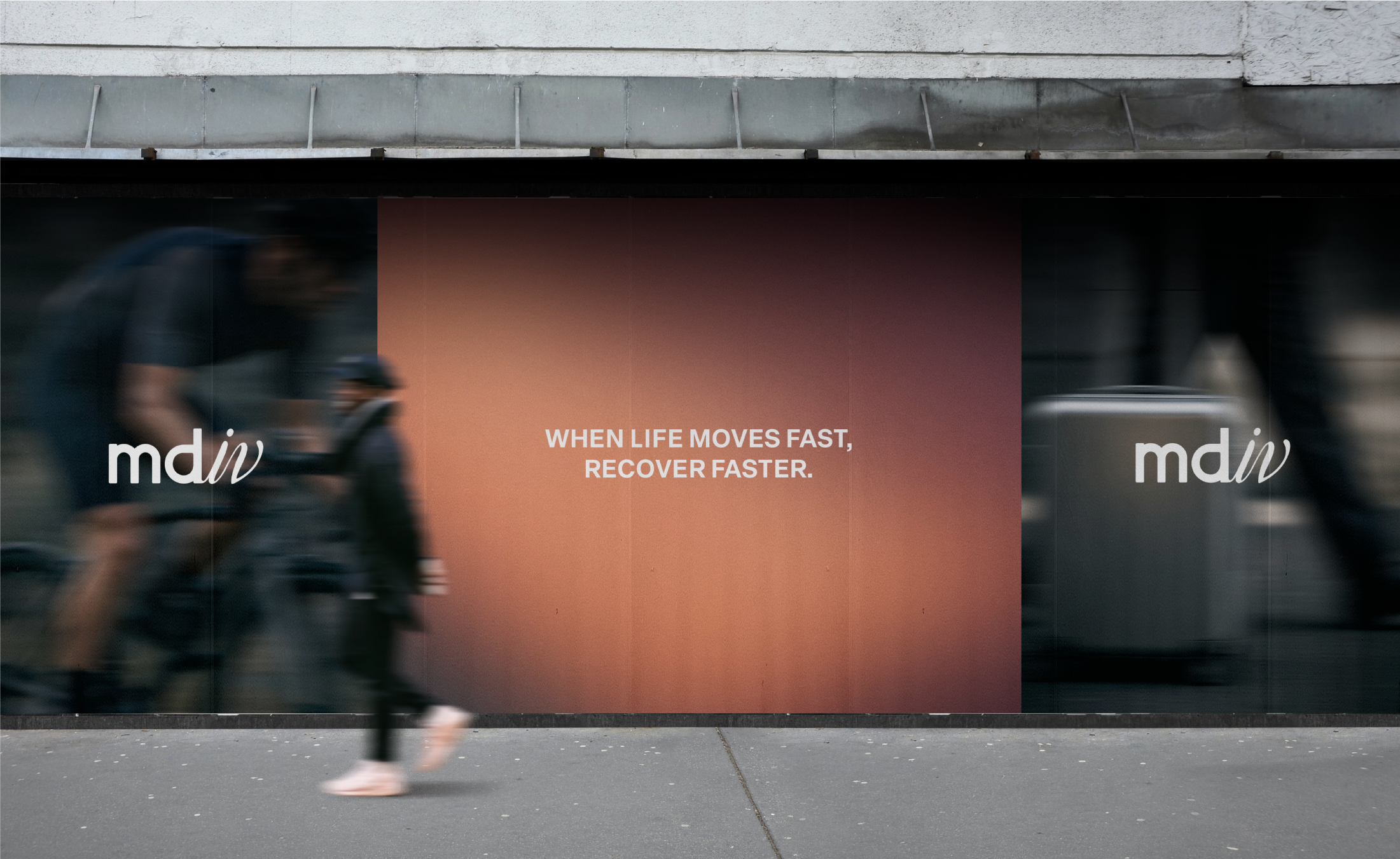 Blurred image of pedestrians walking past a sidewalk billboard with an orange gradient graphic displaying the text 'WHEN LIFE MOVES FAST, RECOVER FASTER.' and the logo 'mdiv' on it.