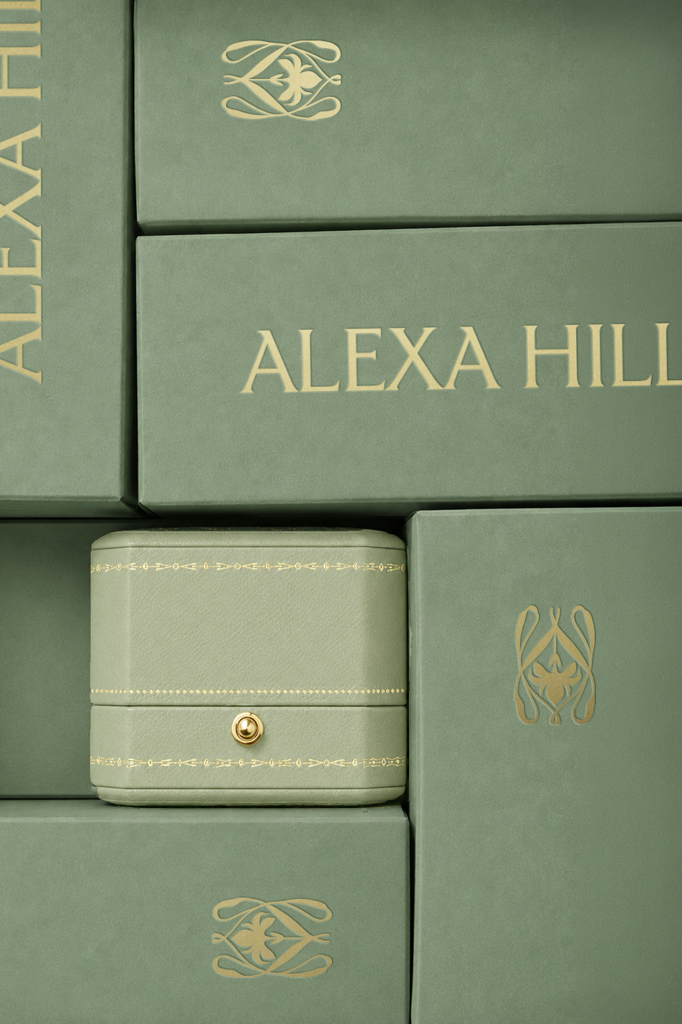 A jewelry box nested amongst green colored branded packaging with gold foil printing of the Alexa Hill logos.