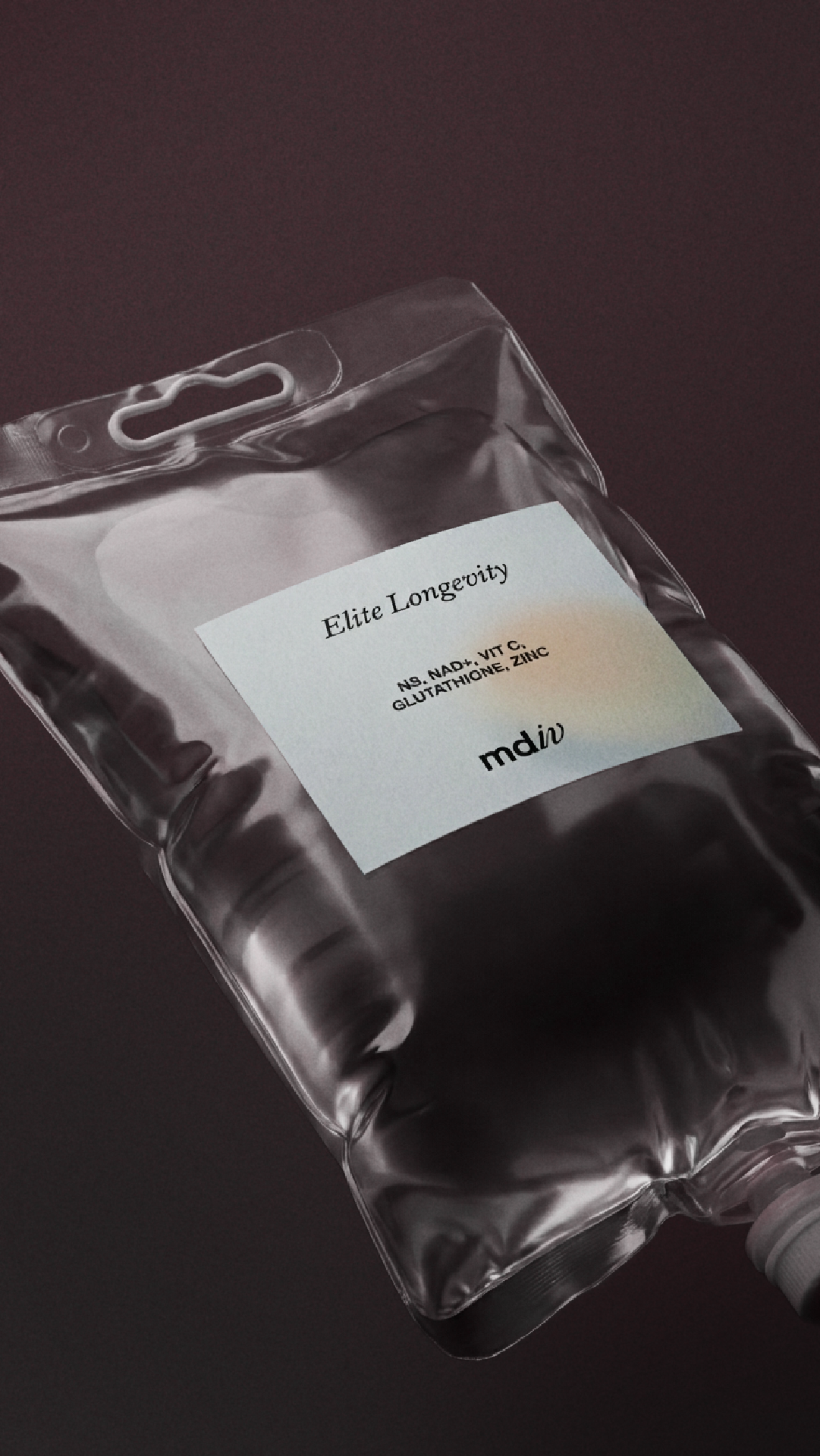 An IV bag with a branded label for 'Elite Longevity' with ingredients niacinamide, vitamin C, glutathione, and zinc, placed on a dark surface.