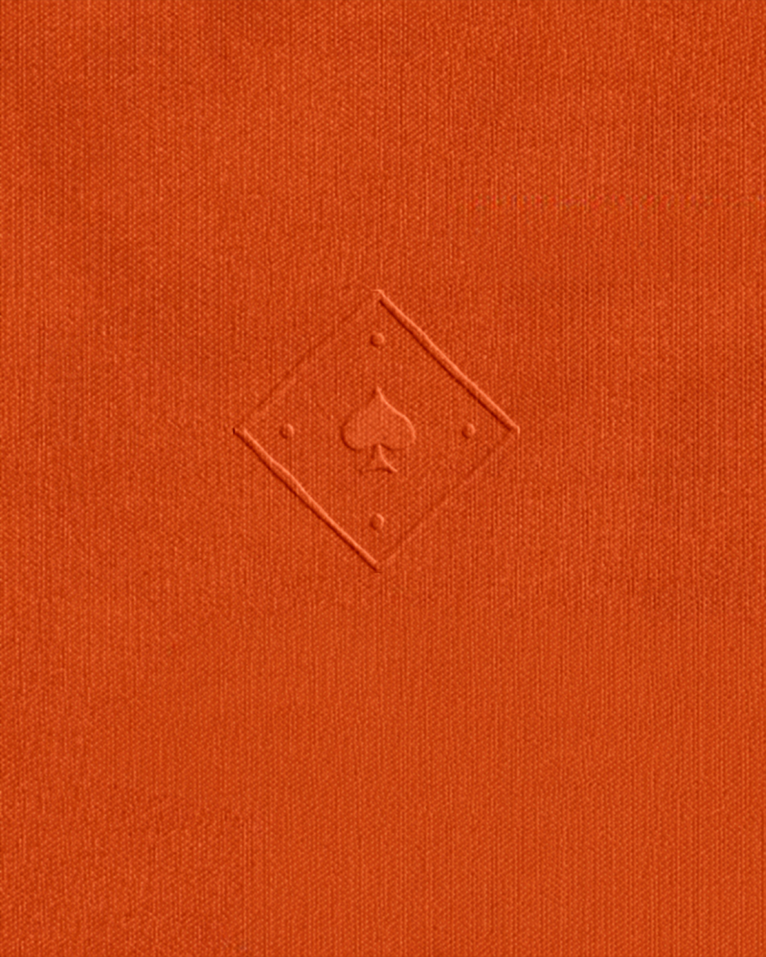 Close-up of a red-orange linen covered menu with an imprinted In Spades logo.