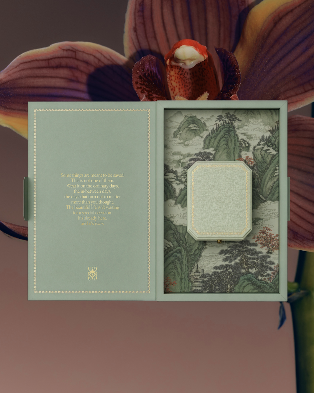 Open jewelry packaging with inlay branded art inspired by asian pattern and drawings, alongside a branded note with gold foil accents.