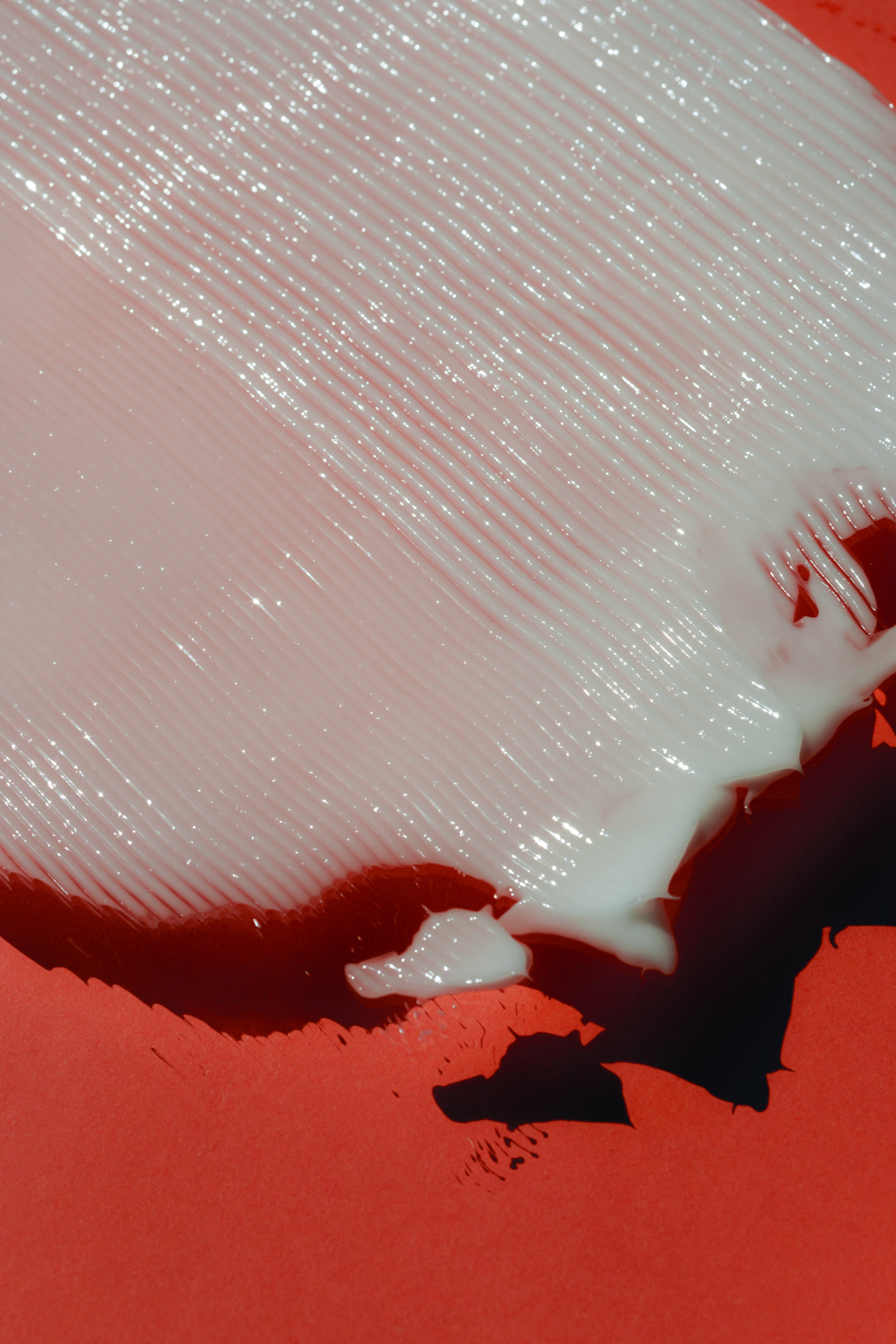 Close-up of a skincare cream smeared over a red background