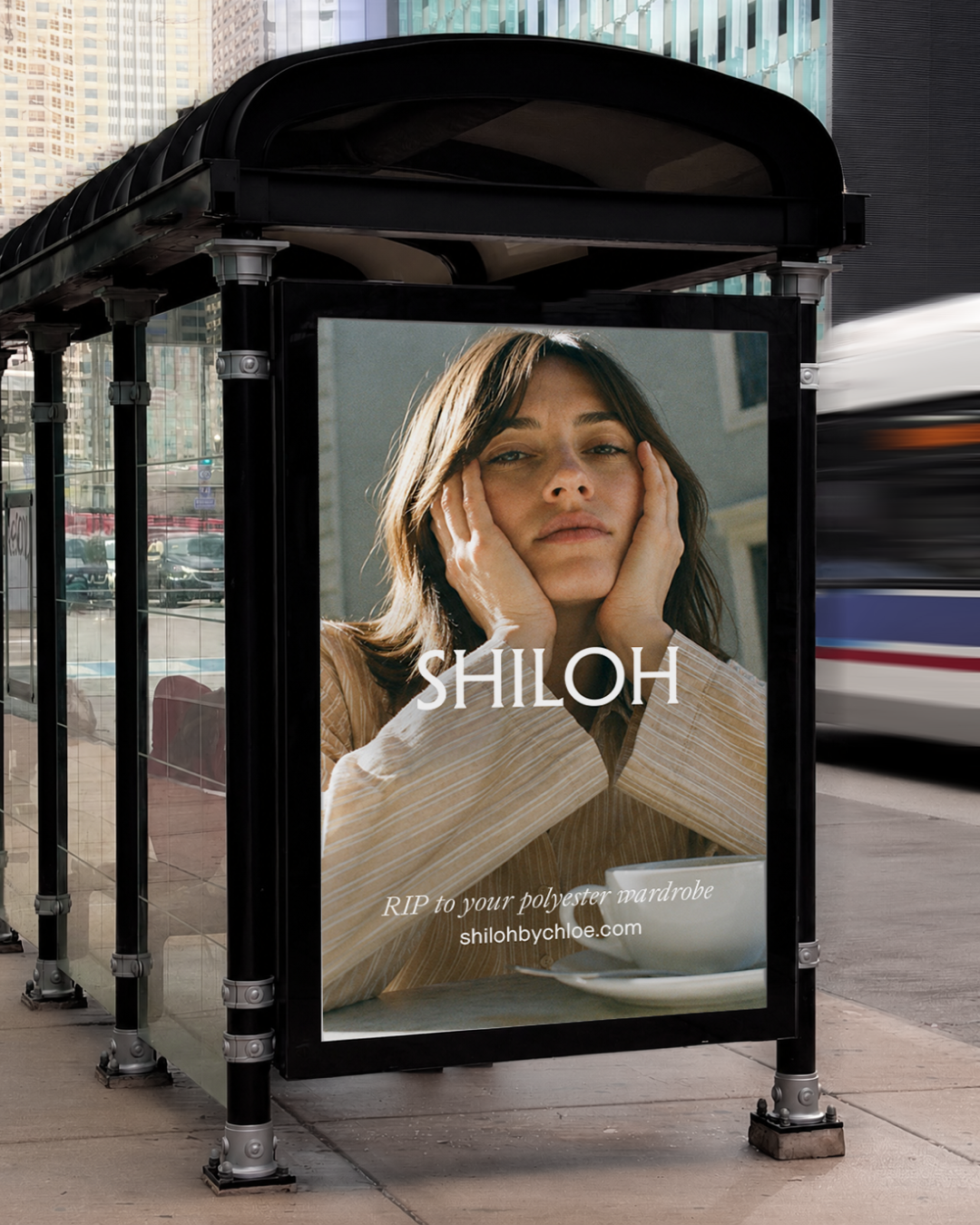 An advertisement on a bus shelter featuring a woman with brown hair, looking tired with hands on her face, and the Shiloh by Chloe logo with a note "RIP to your polyester wardrobe" shilohbychloe.com.