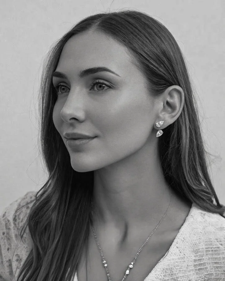 Black and white portrait of a woman with long hair, wearing earrings and a necklace, looking slightly to the side.