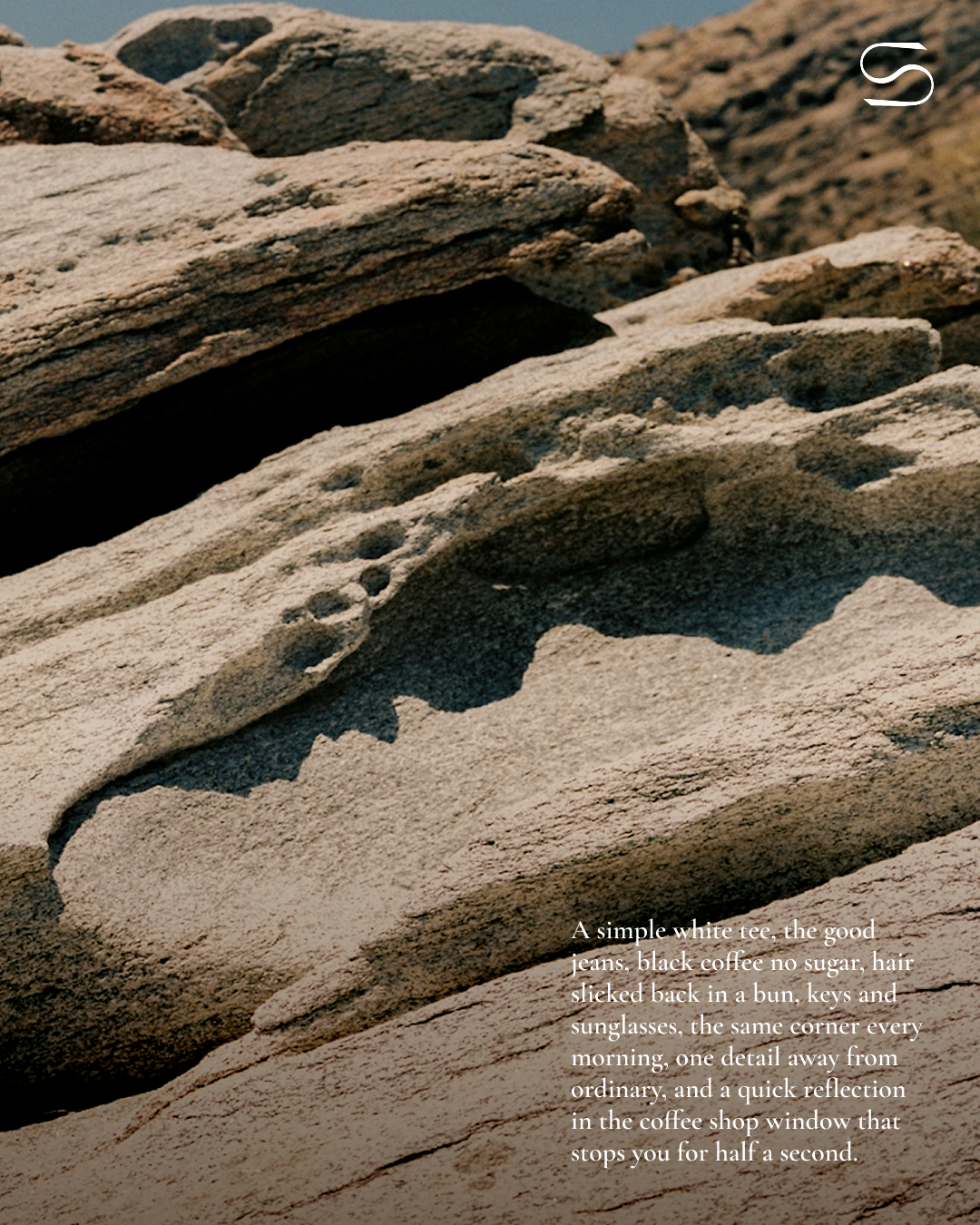 Close-up of textured, layered rocks with shadows, beneath a clear sky with SELA brand messaging overlayed in the bottom right corner.