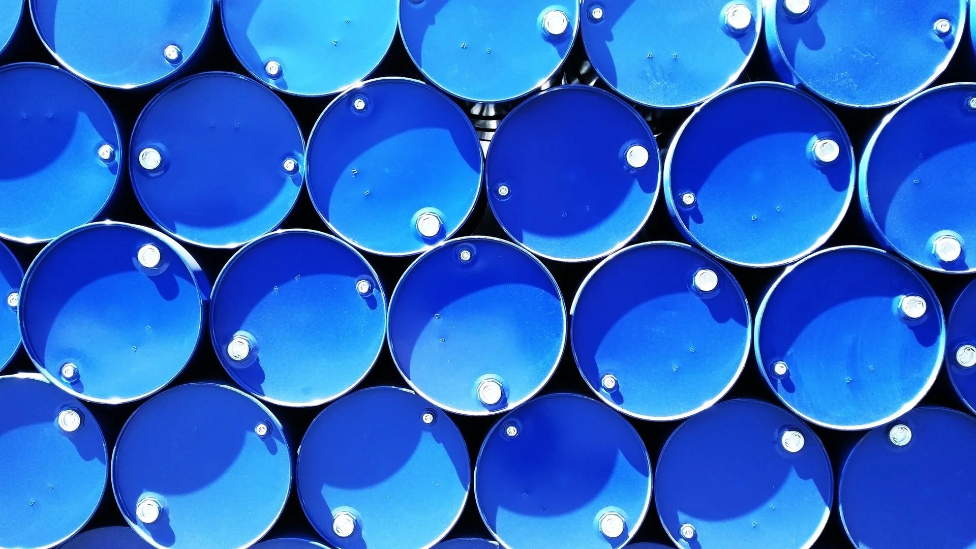 Rows of blue industrial steel drums stacked together for the storage and transportation of chemicals or other industrial materials.