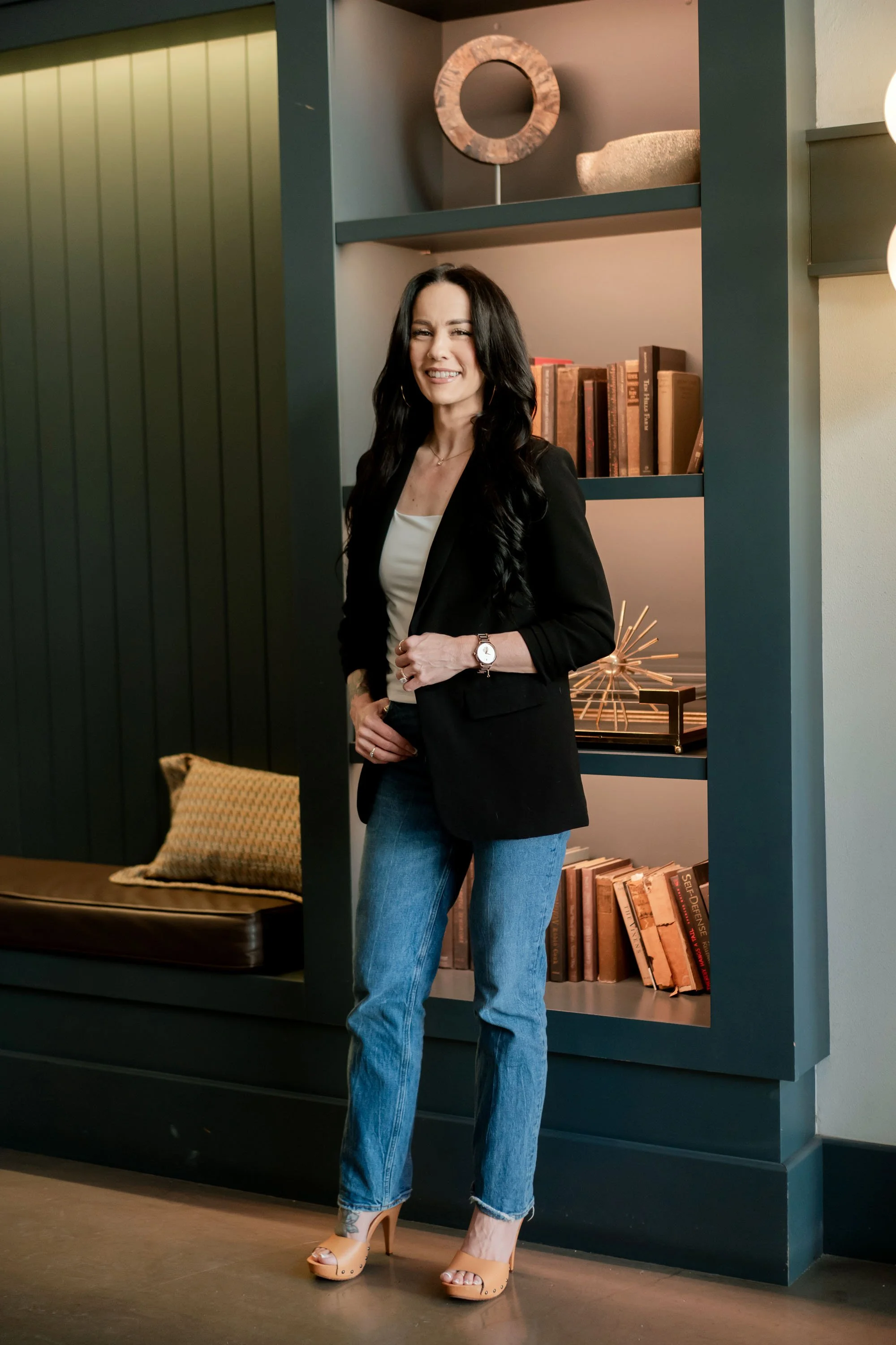 Gwen Taniguchi, business operations strategist and founder of The Operating Standard, standing beside a bookshelf.