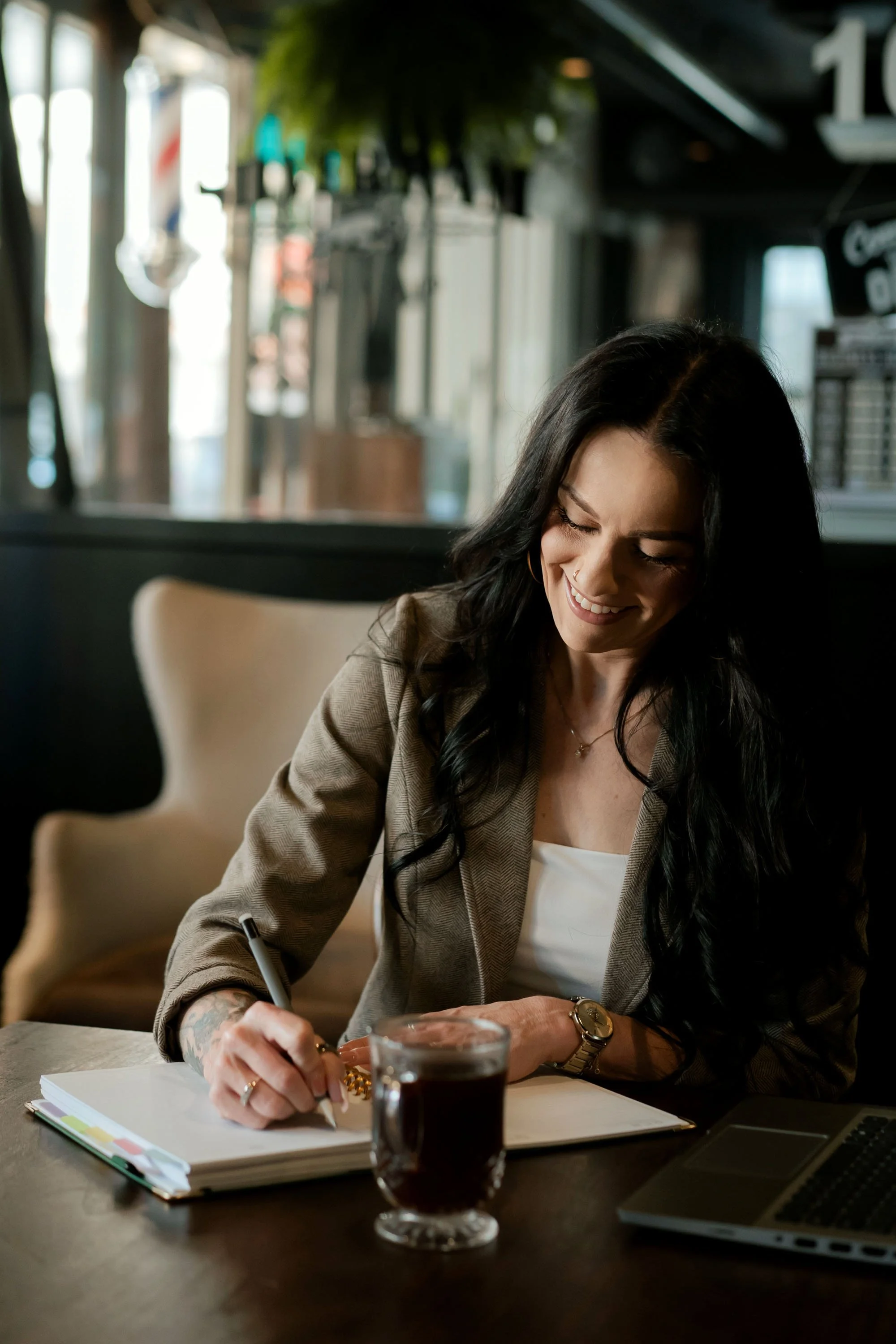 Gwen Taniguchi, founder of The Operating Standard, writing in a notebook while working at a café.
