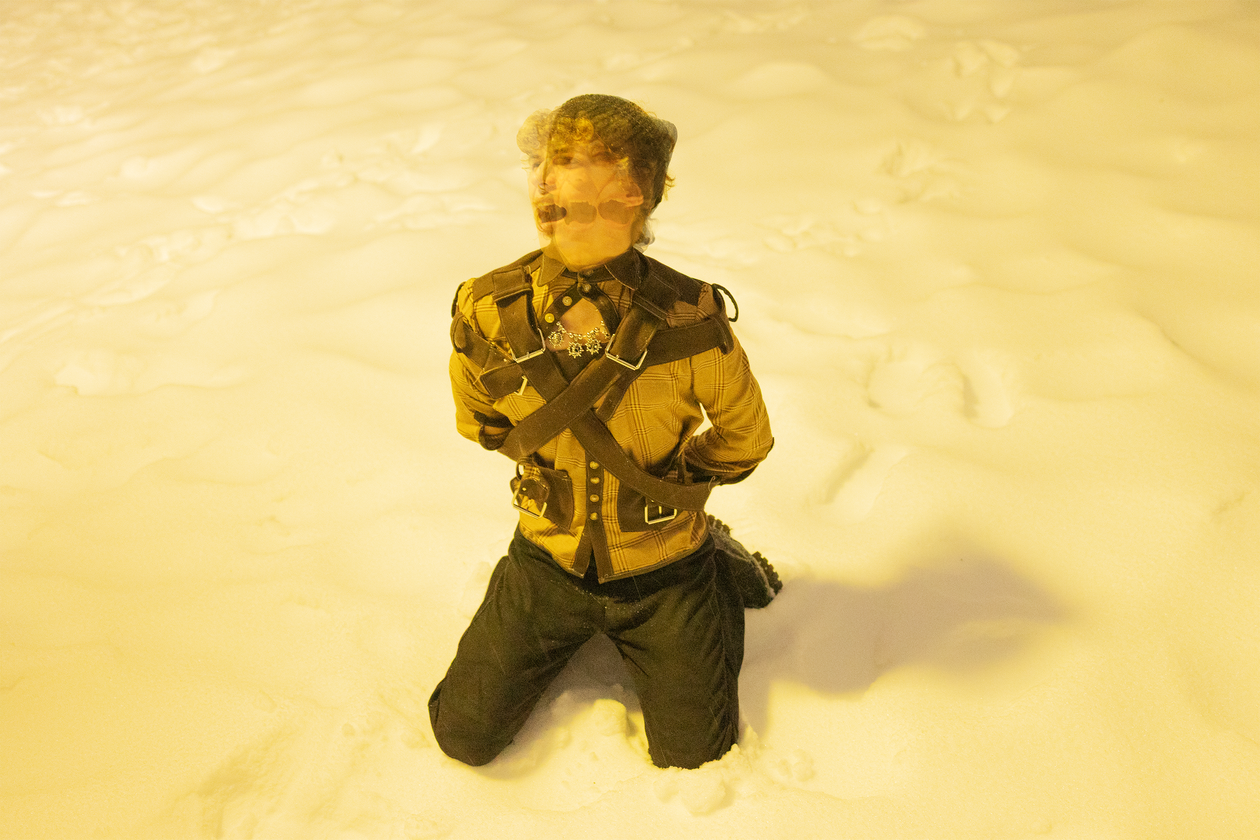 Person kneeling in snow with a blurred background, dressed in winter clothing.