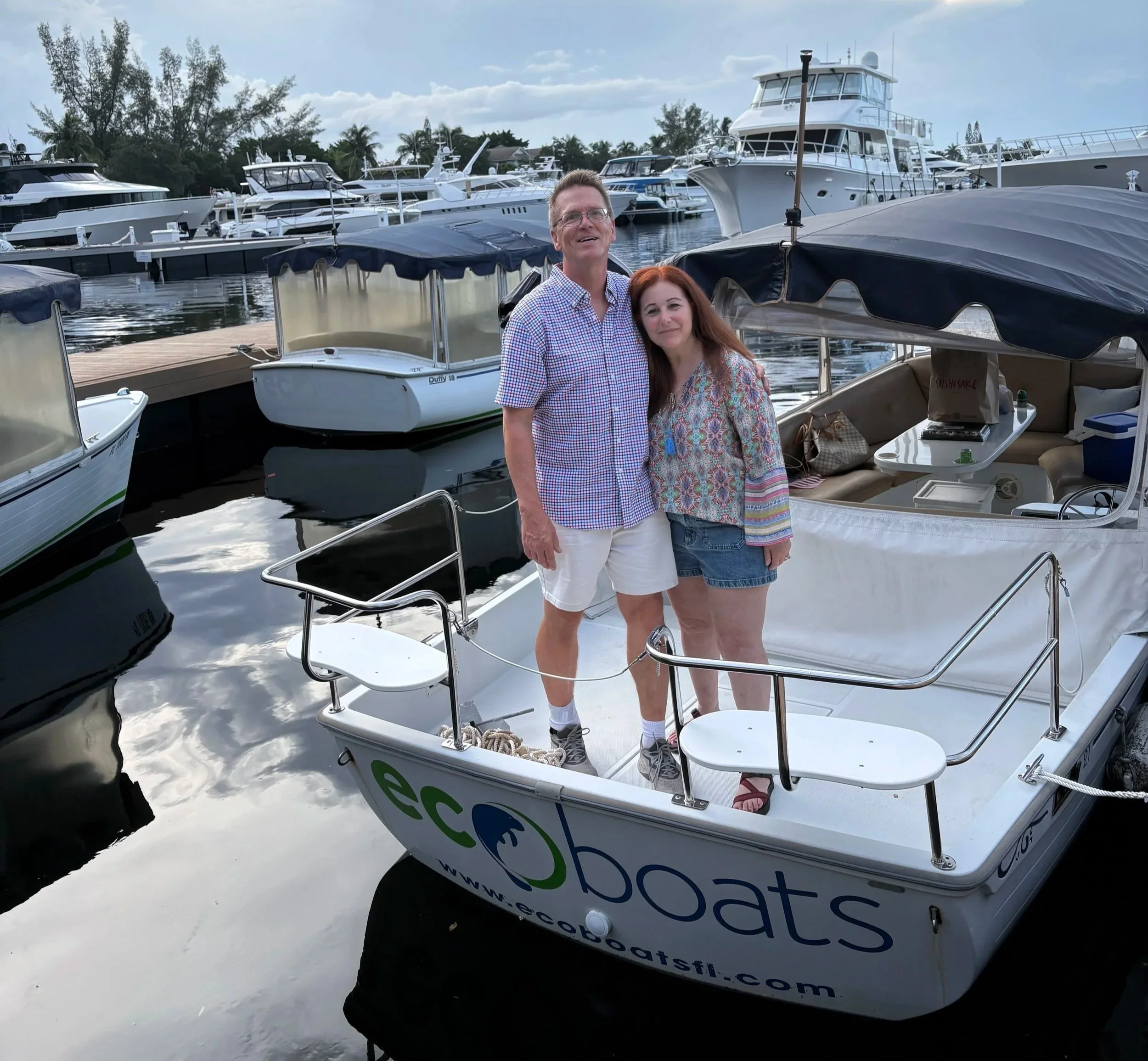 EcoBoats team members standing aboard a Duffy electric boat at a Fort Lauderdale marina dock