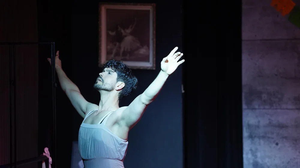 Male ballet dancer with arms extended in a dance pose on stage