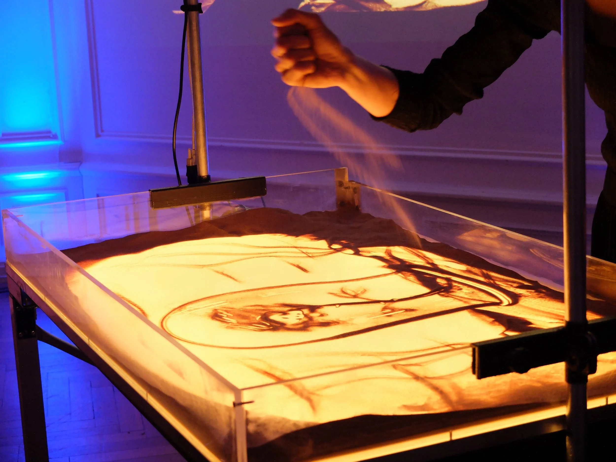 Le mani di Nadia Pretto al lavoro sulla sabbia, con il disegno che prende forma sul piano luminoso, spettacolo dedicato al Piccolo Principe, Strasburgo