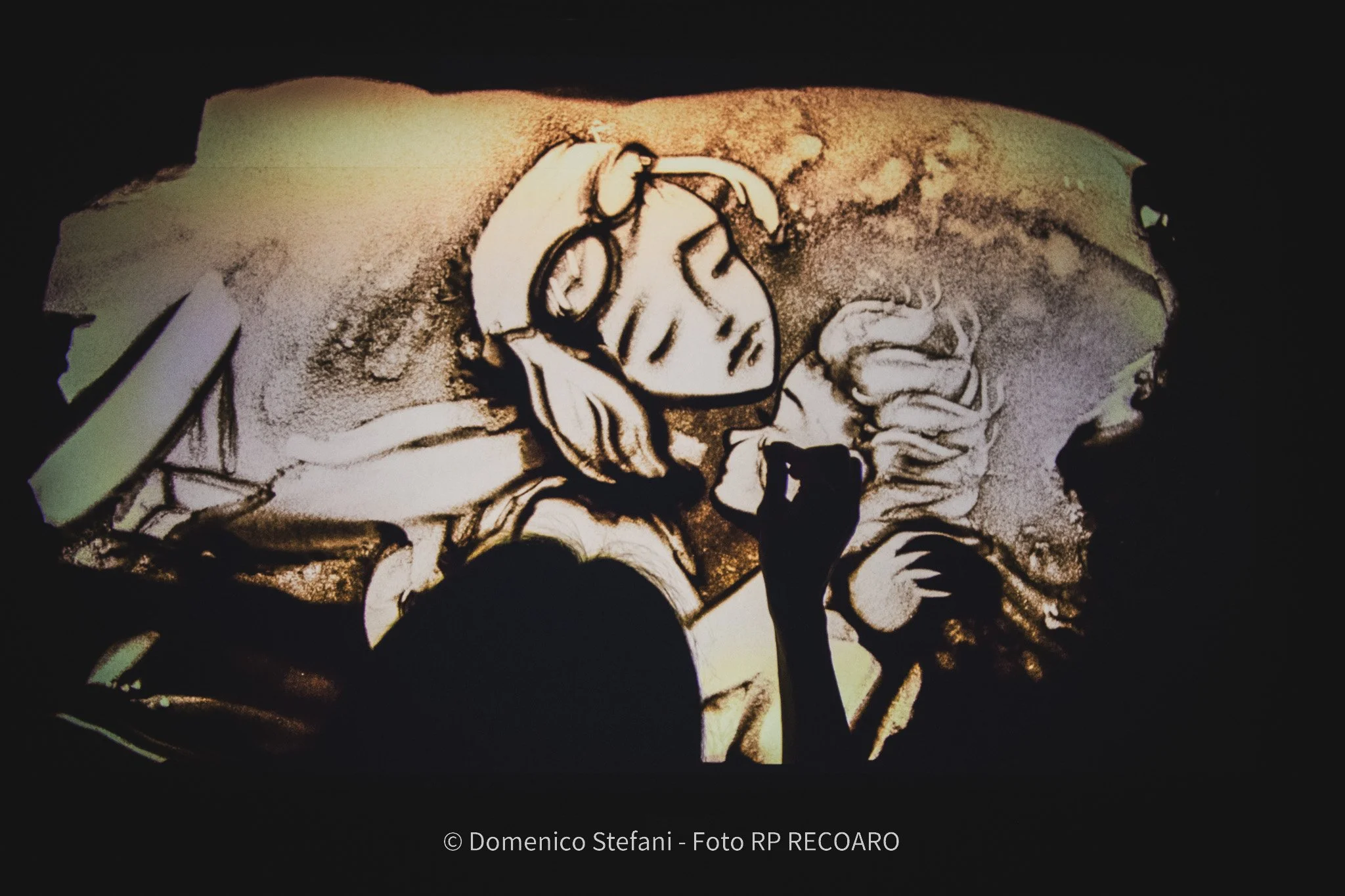 Il Piccolo Principe proiettato sul grande schermo sul palco, spettacolo di sand art di Nadia Pretto con voce narrante. Foto Domenico Stellari · MP Record.