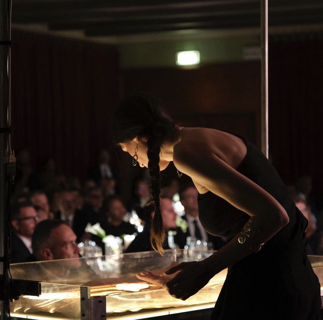 Nadia Pretto disegna nella sabbia davanti agli ospiti seduti ai tavoli durante una cena di gala