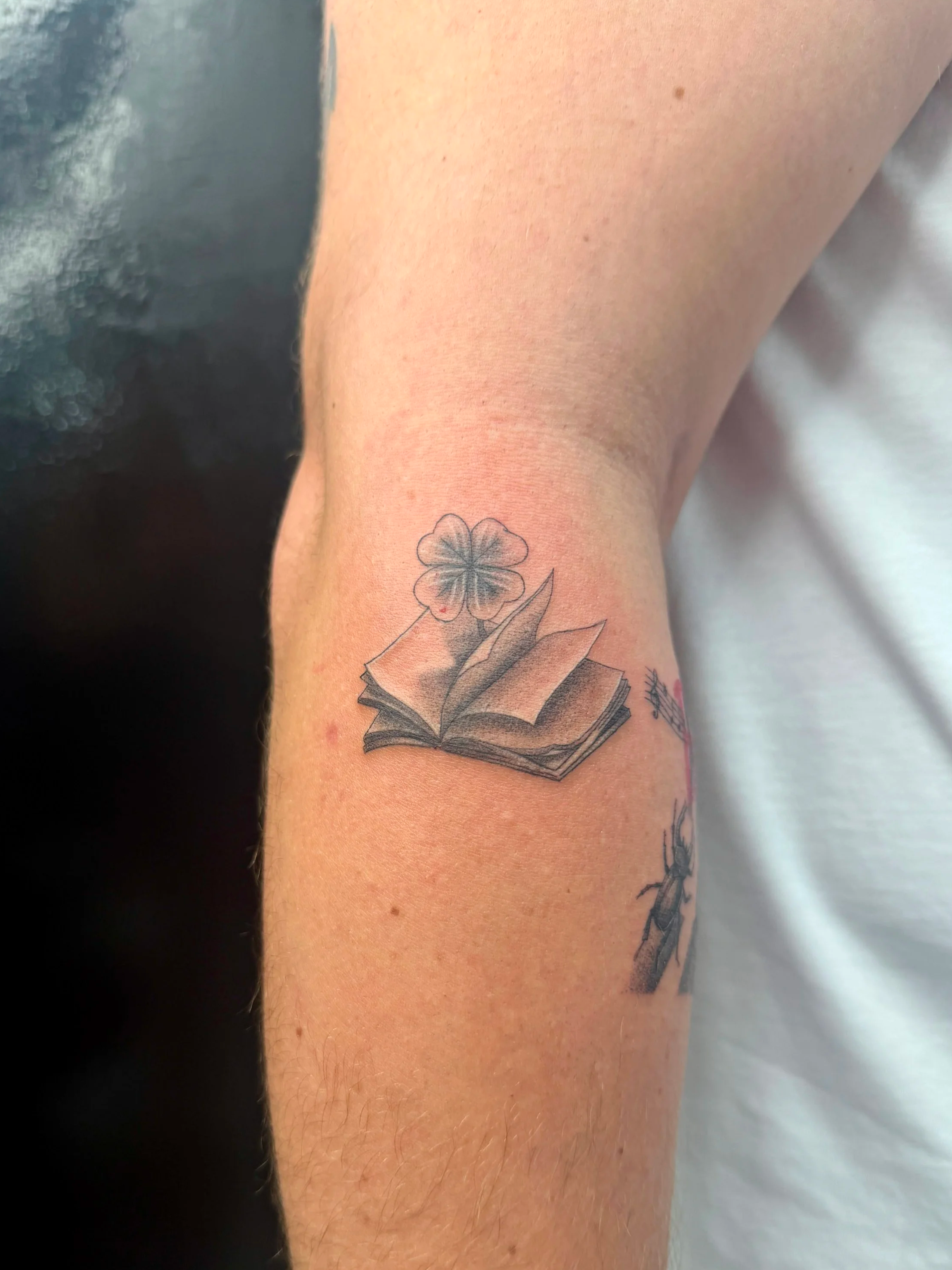 A tattoo of a flower and an open book on the wrist.