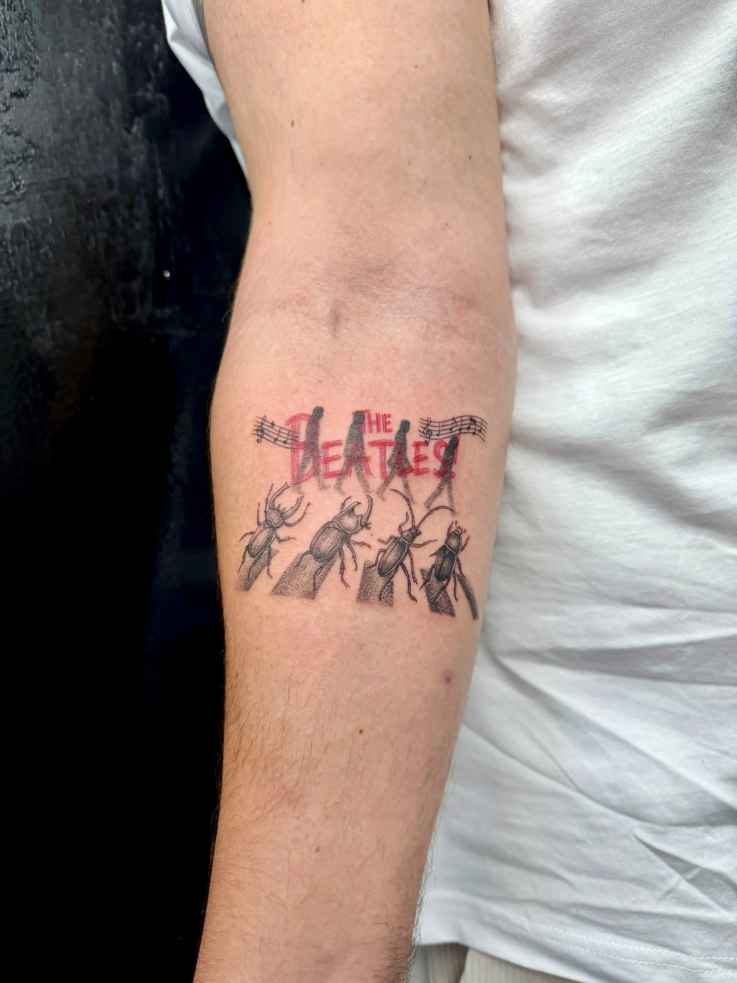 A tattoo of The Beatles, with insect illustrations below the words.