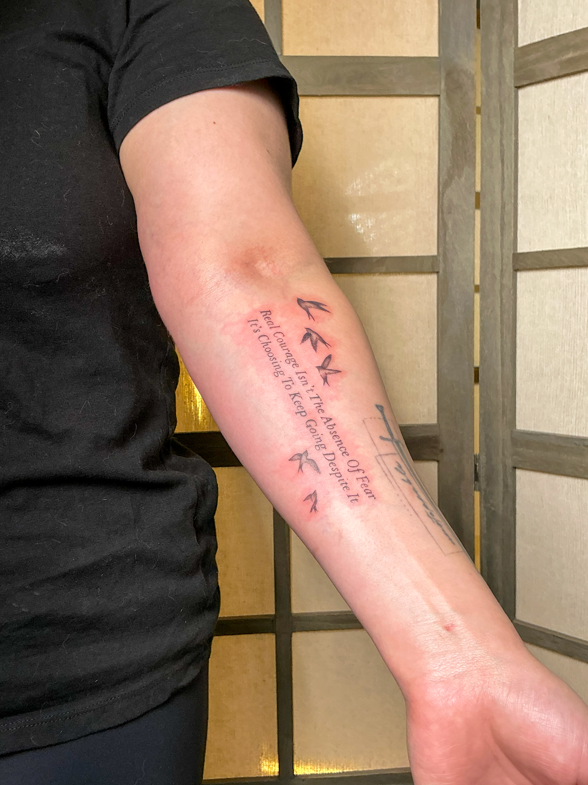 A tattoo of flying birds and a quote in cursive font.
