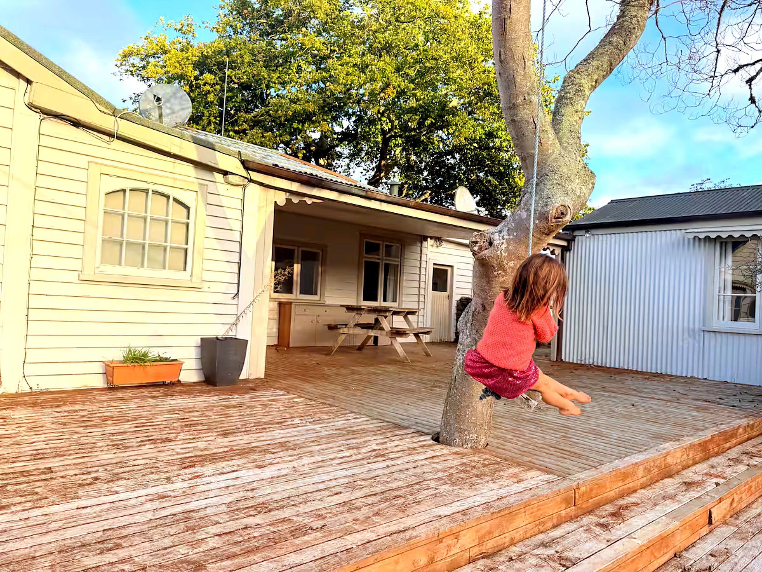 Girl enjoying Farmstead decked area with kids tree swing at Rathmoy Farmhouse in Rangitikei near Manawatu.