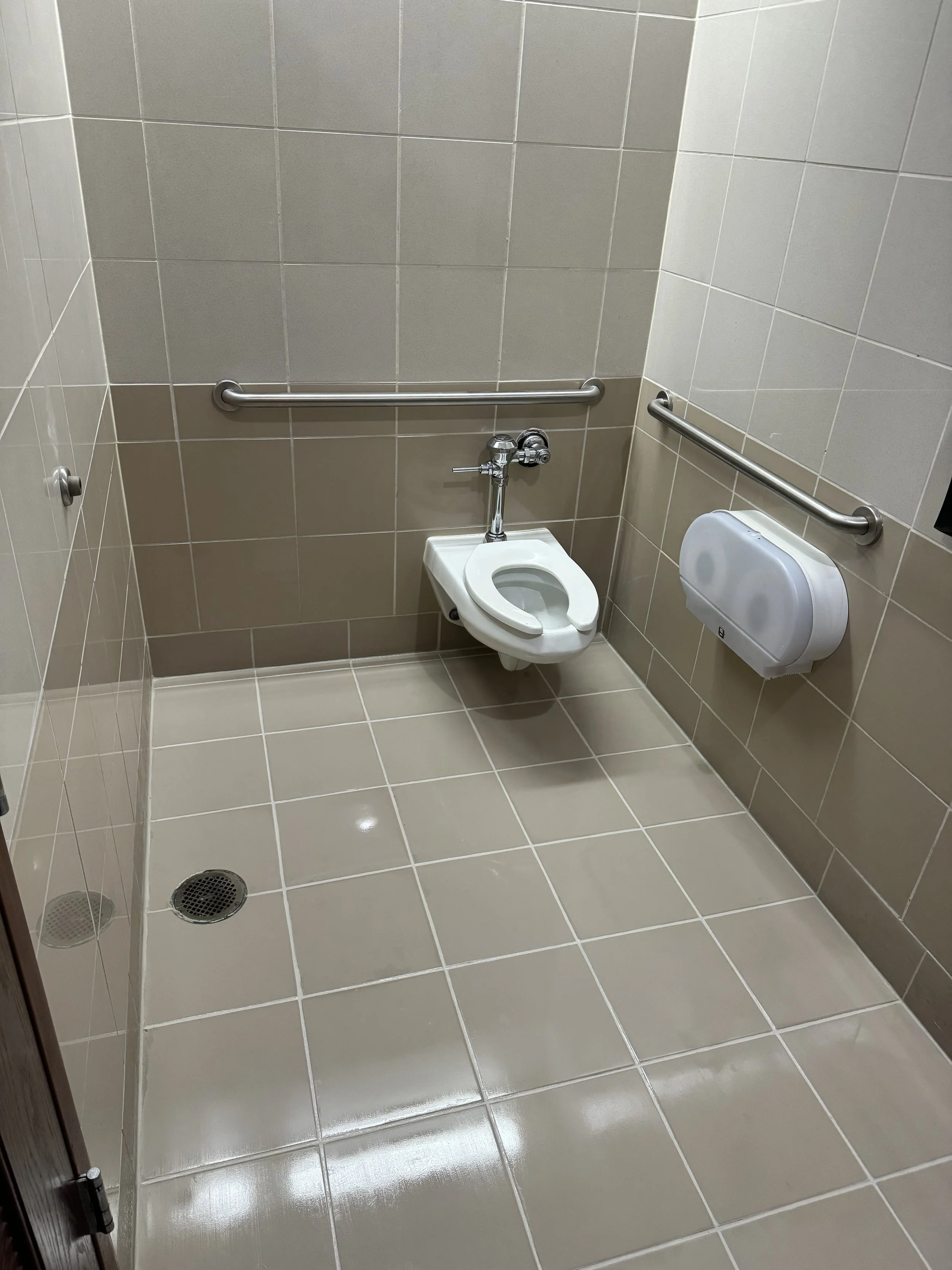 Accessible commercial bathroom with sanitized beige tile and grout in Coral Springs.