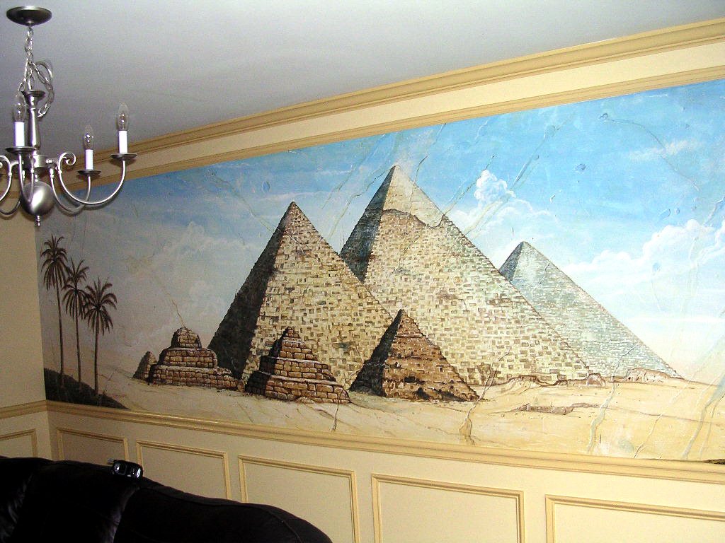 A wall mural depicting the Egyptian pyramids and palm trees in a desert landscape with a bright blue sky and clouds.