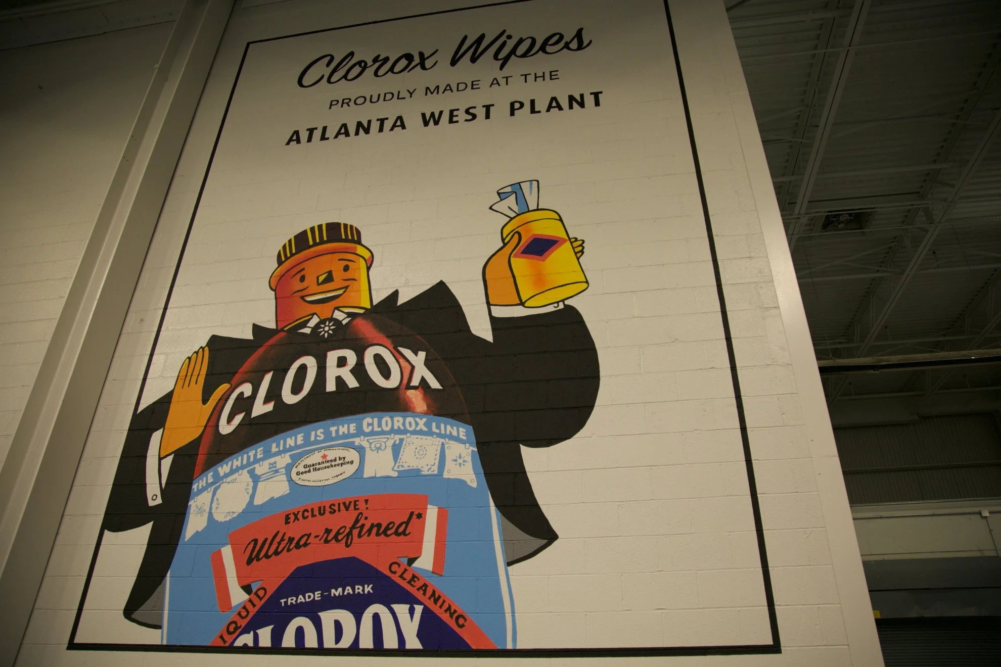 A large billboard advertising Clorox wipes, featuring cartoon characters and text highlighting the product as made at the Atlanta West Plant and emphasizing quality and cleaning effectiveness.