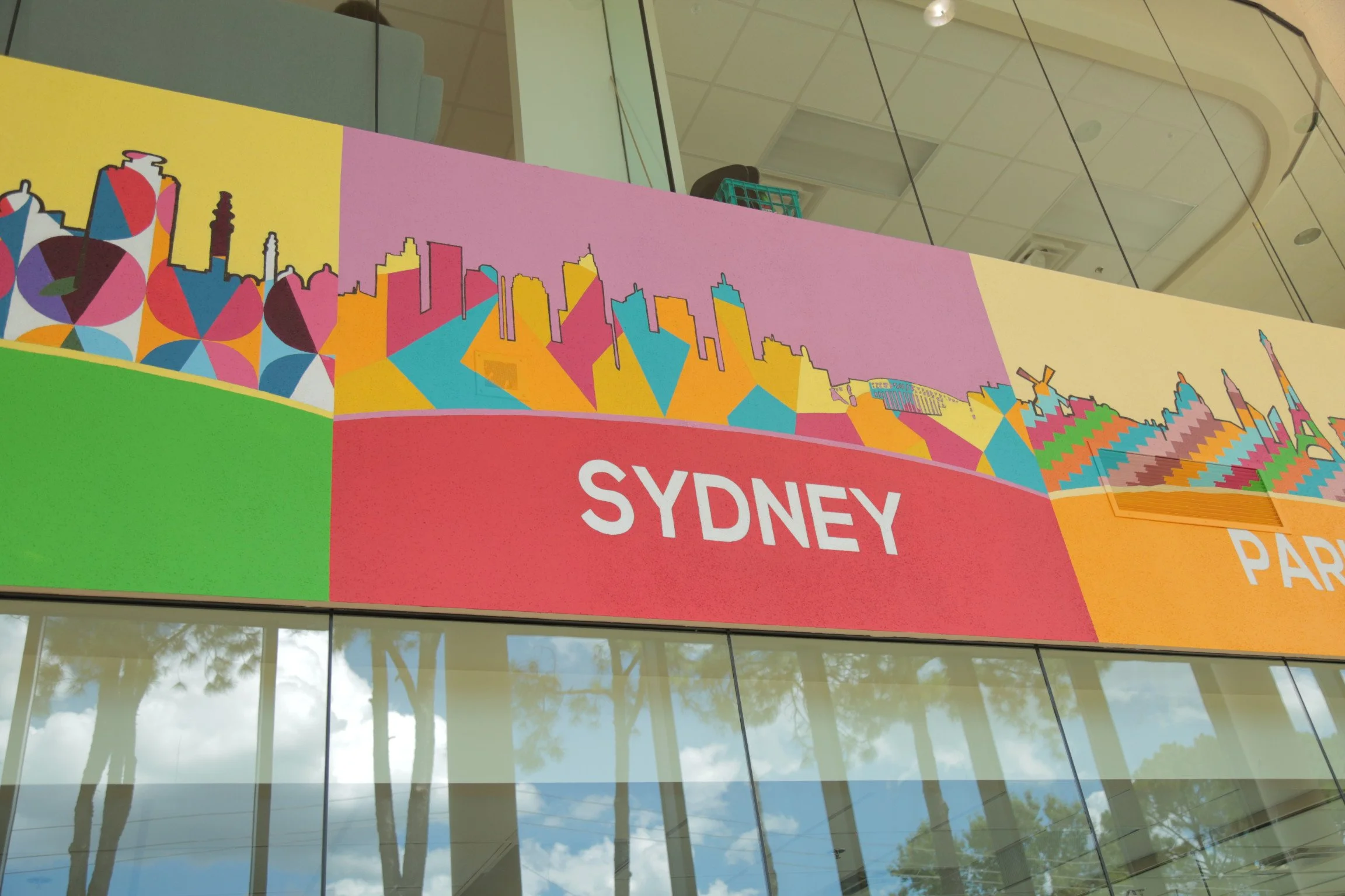 Colorful signboard with abstract cityscape artwork, displaying the words 'Sydney' and 'Park' in white text.