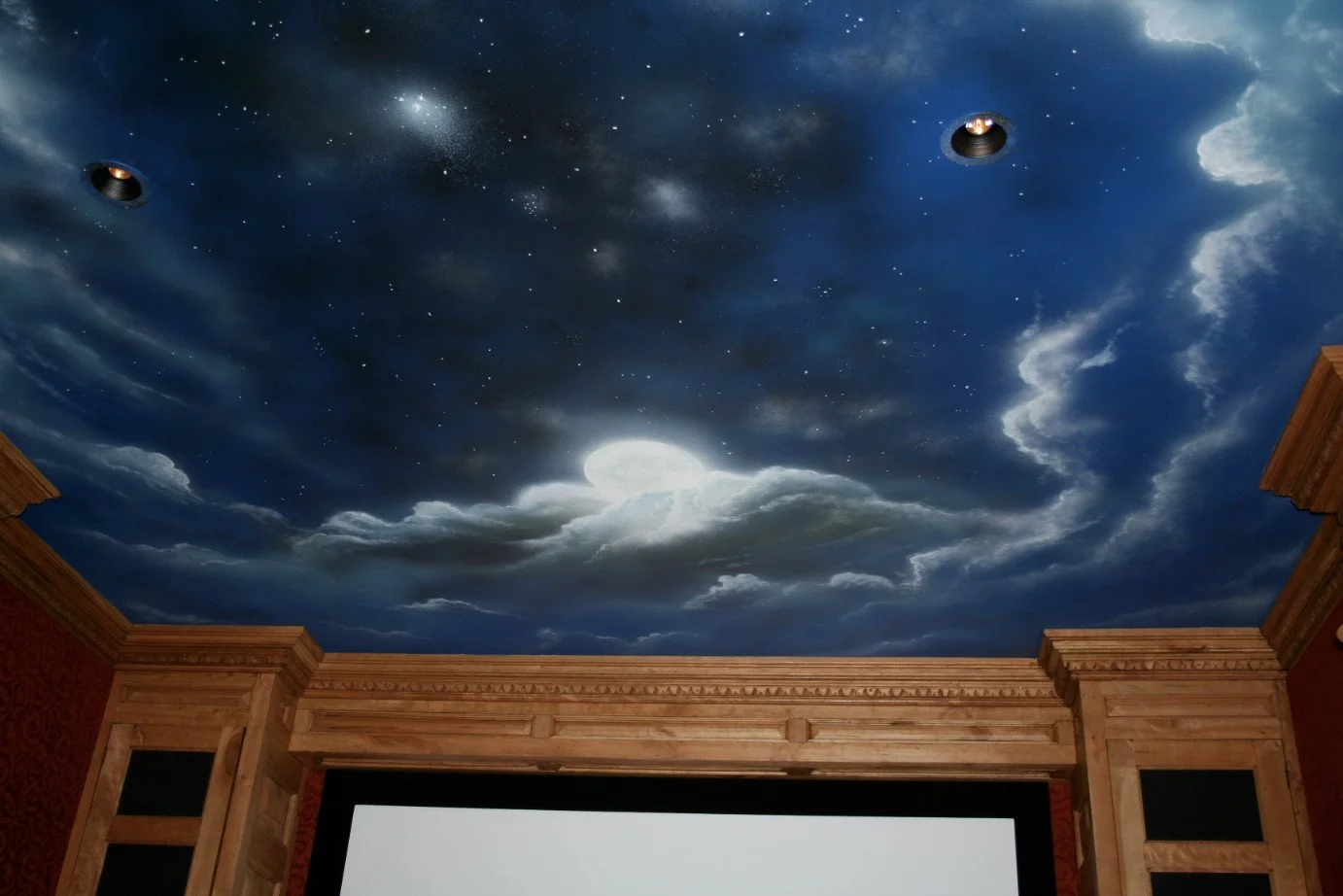 Ceiling painted to resemble a night sky with clouds, stars, a bright moon, and two spotlights.