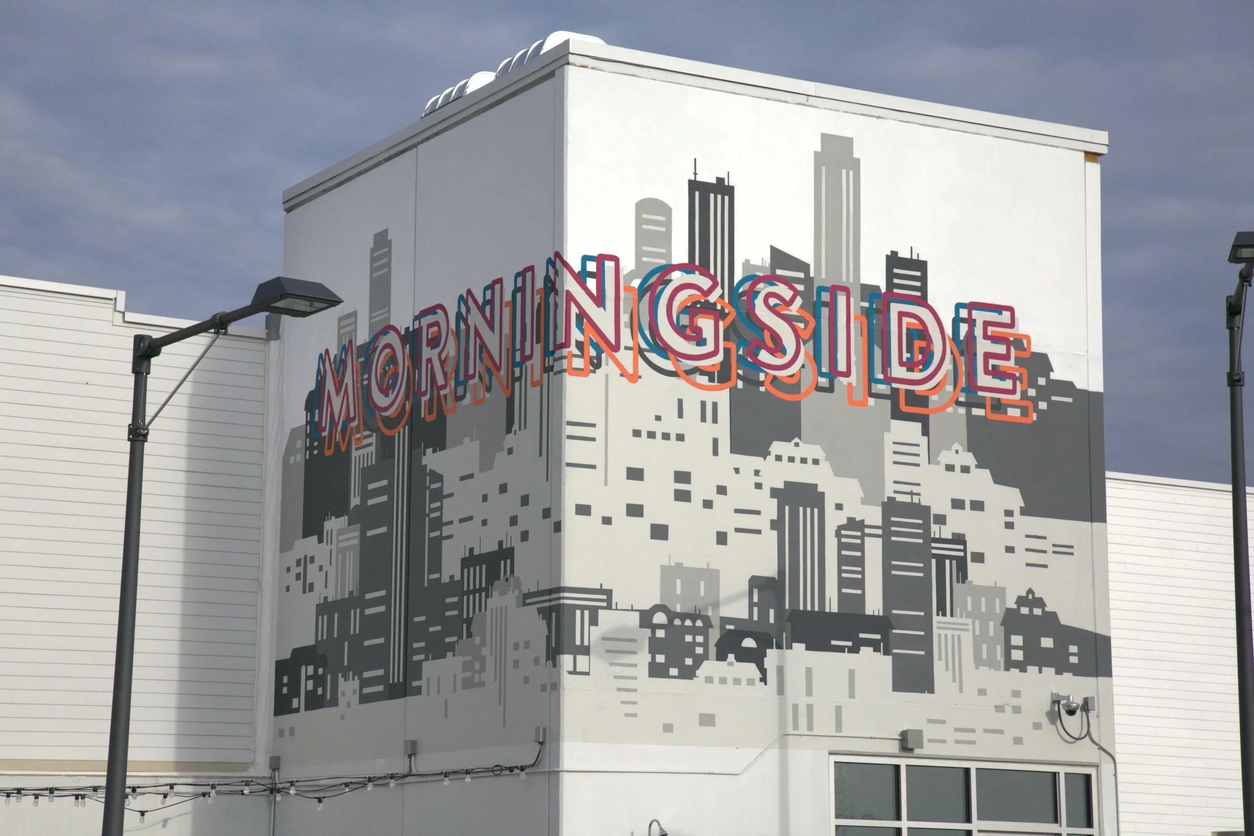 Murals of a city skyline painted on the side of a white building with the words "Morning Side" in colorful letters.