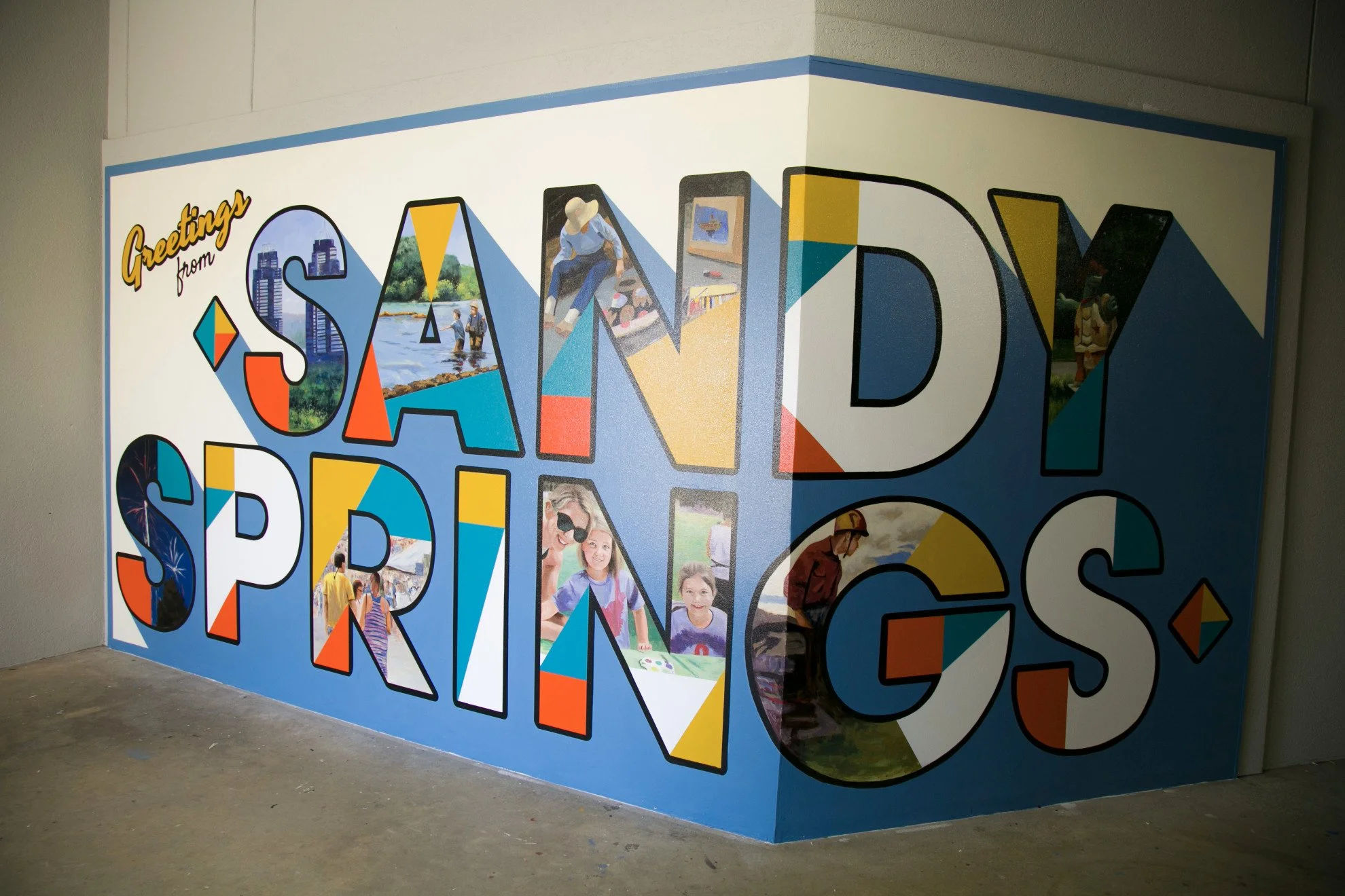Colorful welcome mural with large text reading 'Greetings from SAND SPIRES' and photos of people enjoying outdoor activities.