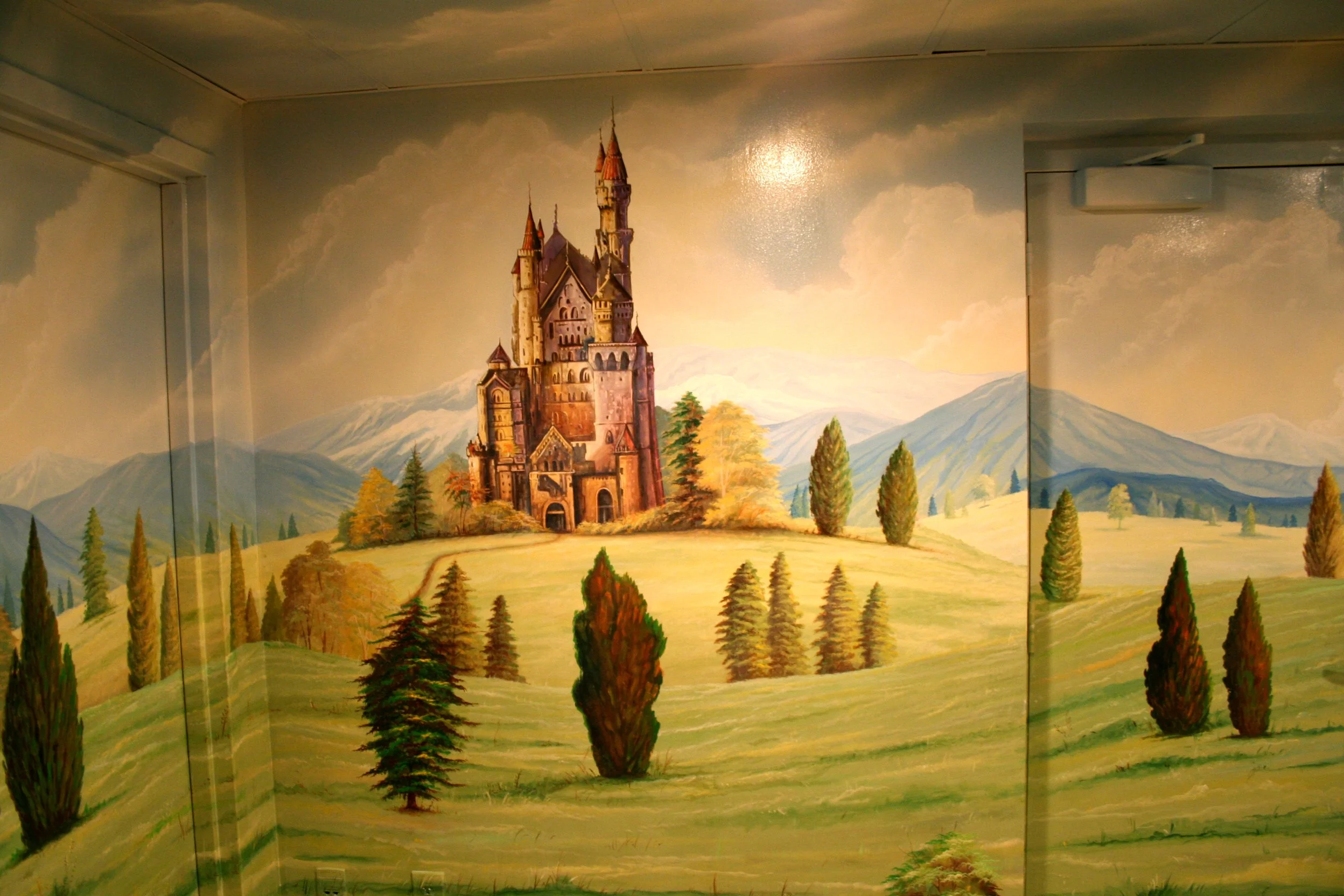 Mural of a fairy tale castle on a landscape wall with mountains, trees, and a sky with clouds.