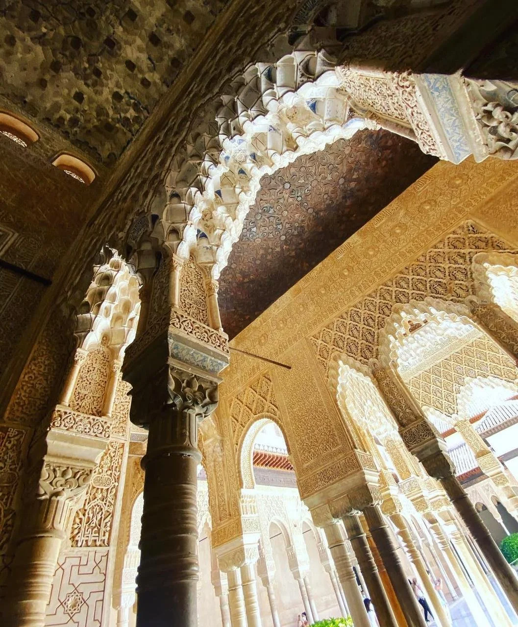 Intricate Islamic architecture with carved arches, columns, and detailed geometric and floral patterns in cream and gold tones.