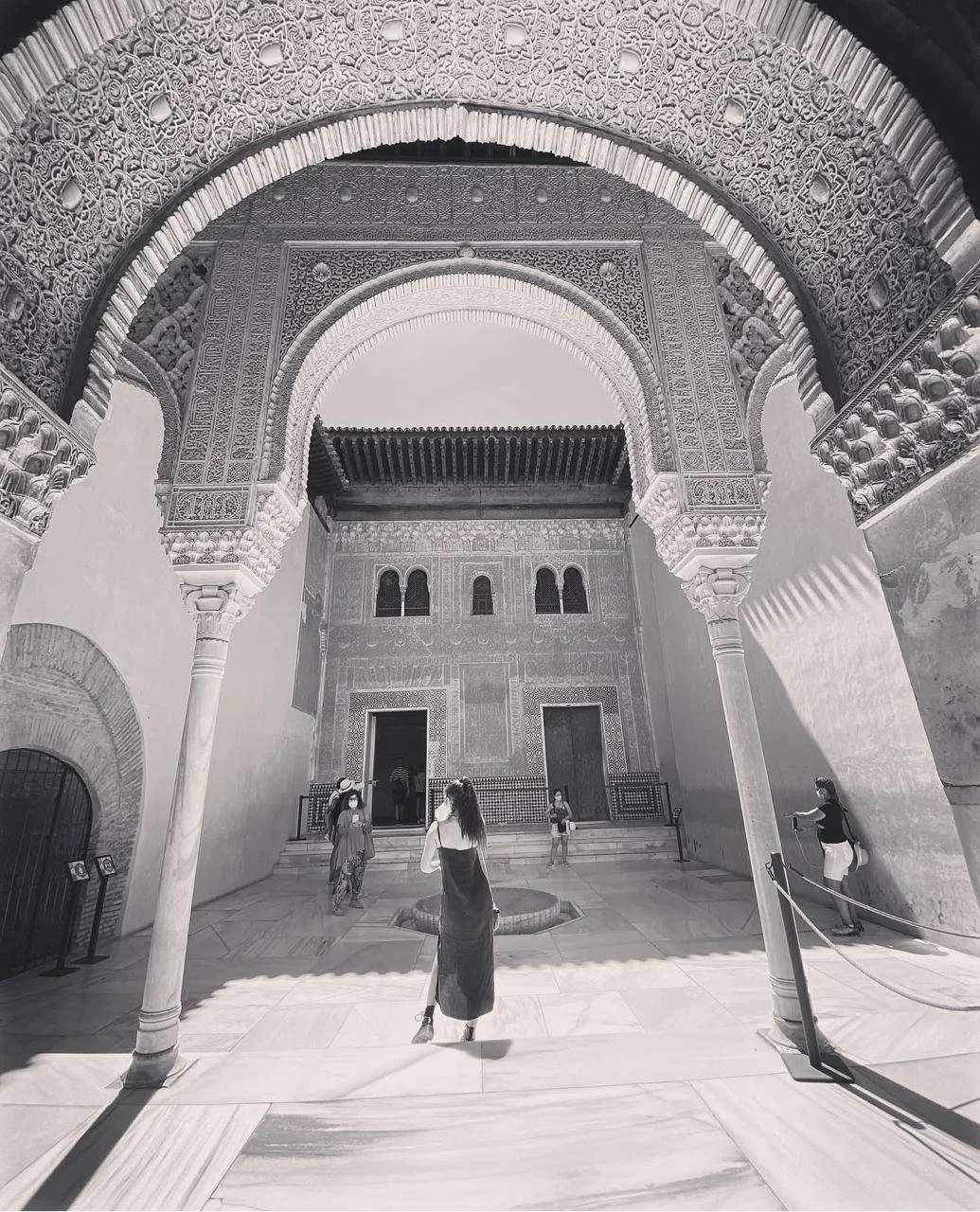 People inside a historical building with ornate arches and intricate decorative details on the walls and ceiling.